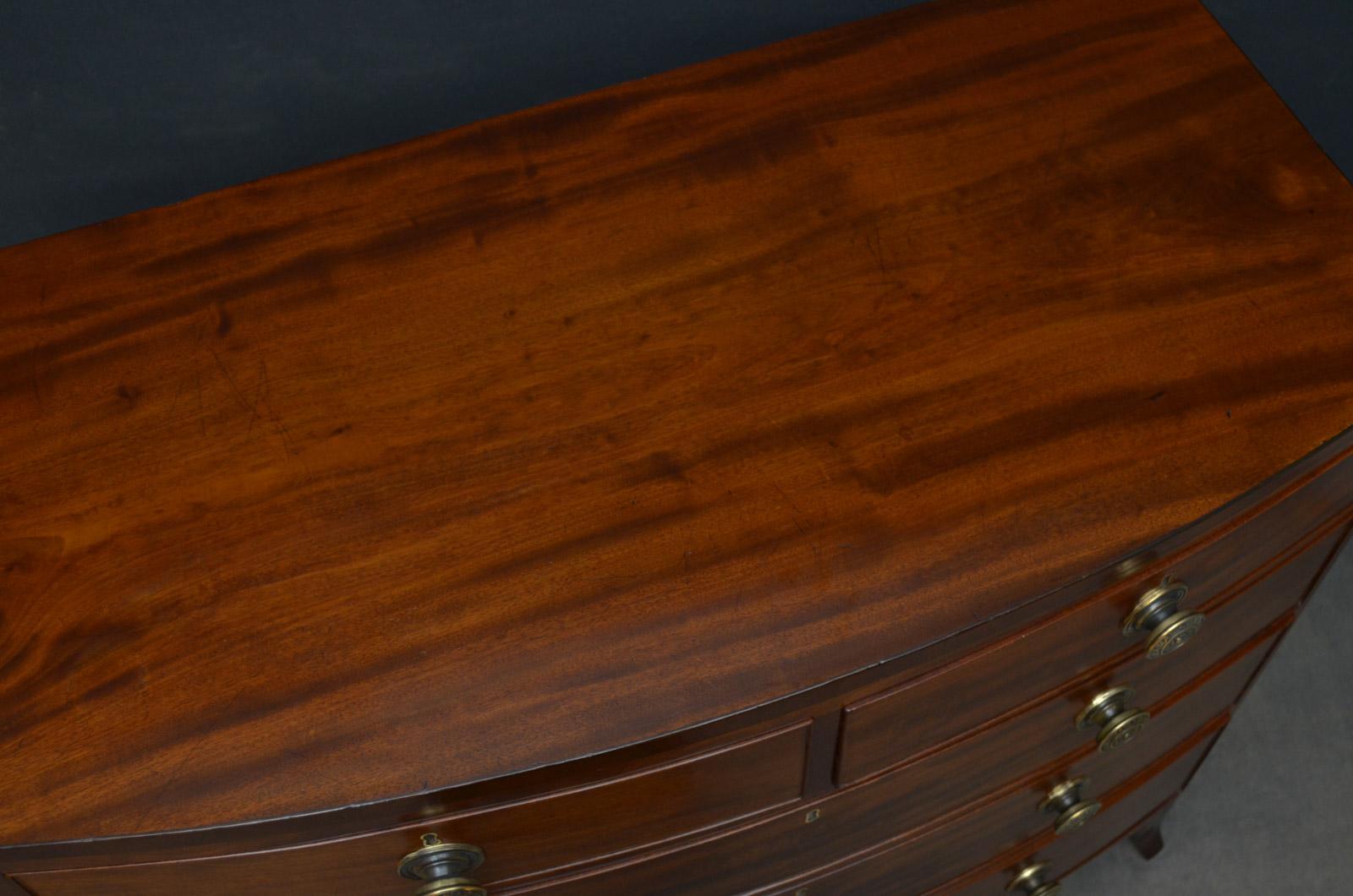 Sn4442 Regency mahogany chest of drawers of bowfronted design, having figured mahogany top above 2 short and 3 long graduated and cockbeaded drawers, all fitted with original brass knobs, standing on splayed feet united by shaped apron. This antique