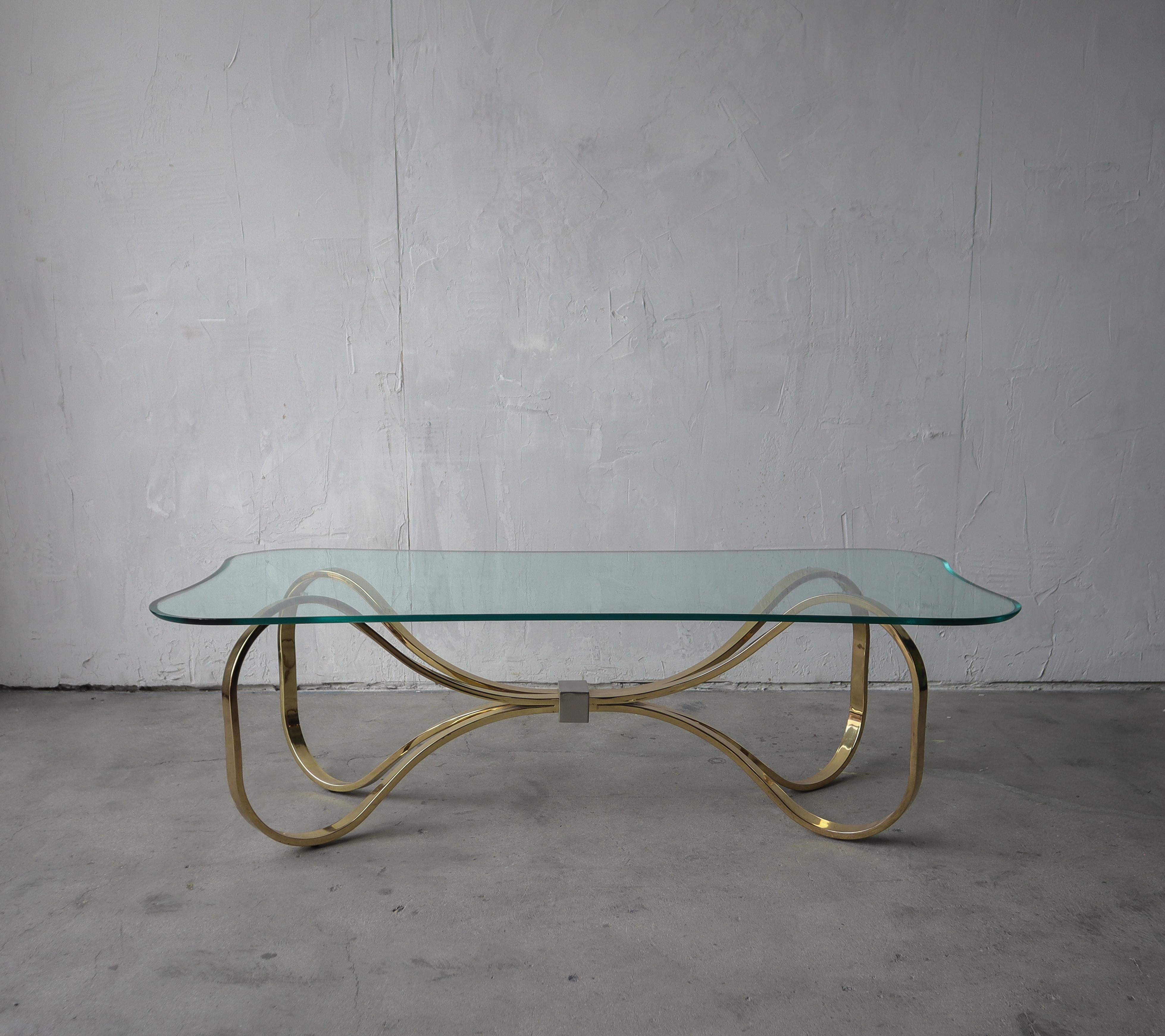 Nice 1980s brass and glass coffee table, shaped like a bow tie. Visually a beautiful table. The curvy design and glass give it a very feminine, classy appeal.

Table is in excellent condition overall, very minimal marks on the glass from use, but