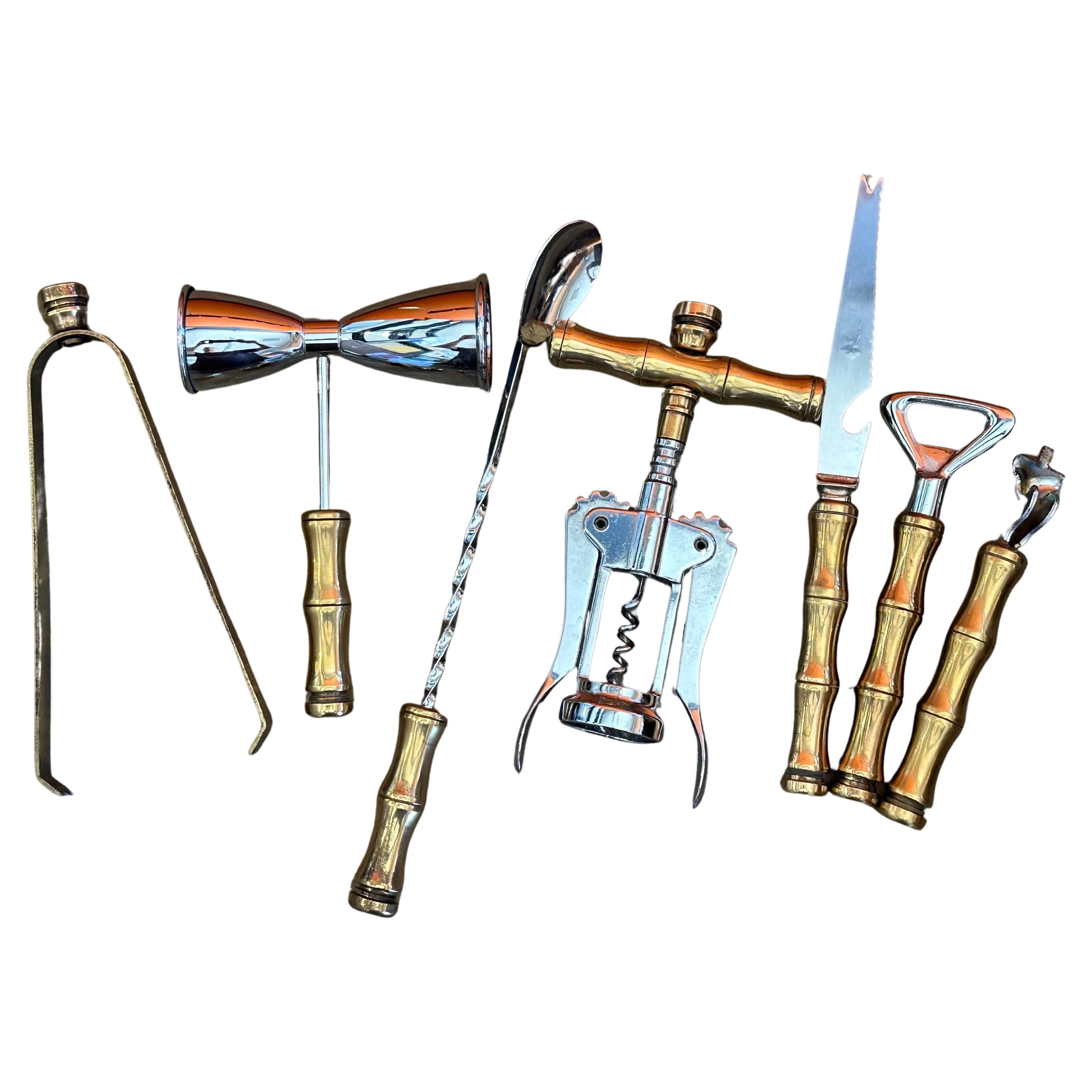 A very cool and extremely well made Hollywood Regency brass, stainless steel and bakelite eight piece cocktail bar tool set by Maxwell Phillips, circa 1970s. The set includes seven bar tools (bottle & can opener, tongs, long stir spoon, knife,