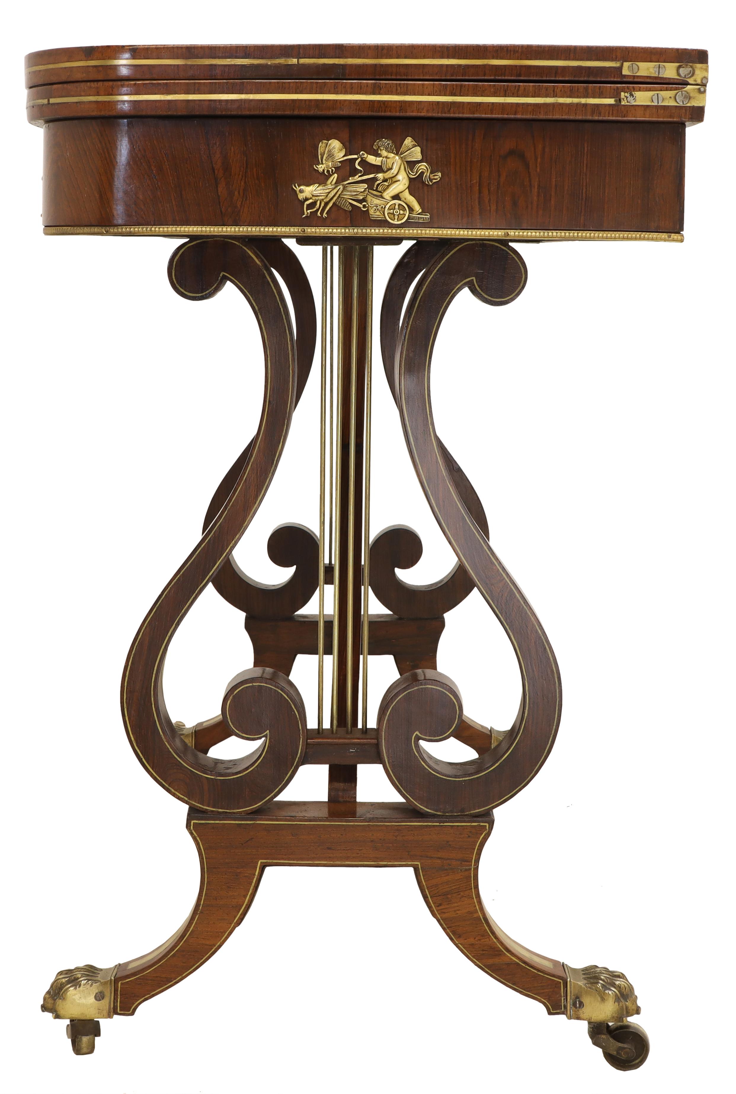 This beautifully carved hardwood table features a swivel top that opens up to reveal the baized playing surface. It is in the manner of John McLean, and is decorated with lyre shaped supports, brass paw sabots and castors. 
(John McLean was a