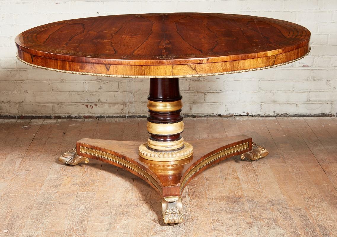 Very fine Regency period Brass inlaid rosewood center table, the richly grained and bookmatched veneer top with ring of brass floral decoration in the manner of George Bullock, the apron with applied brass molding, standing on parcel gilt and