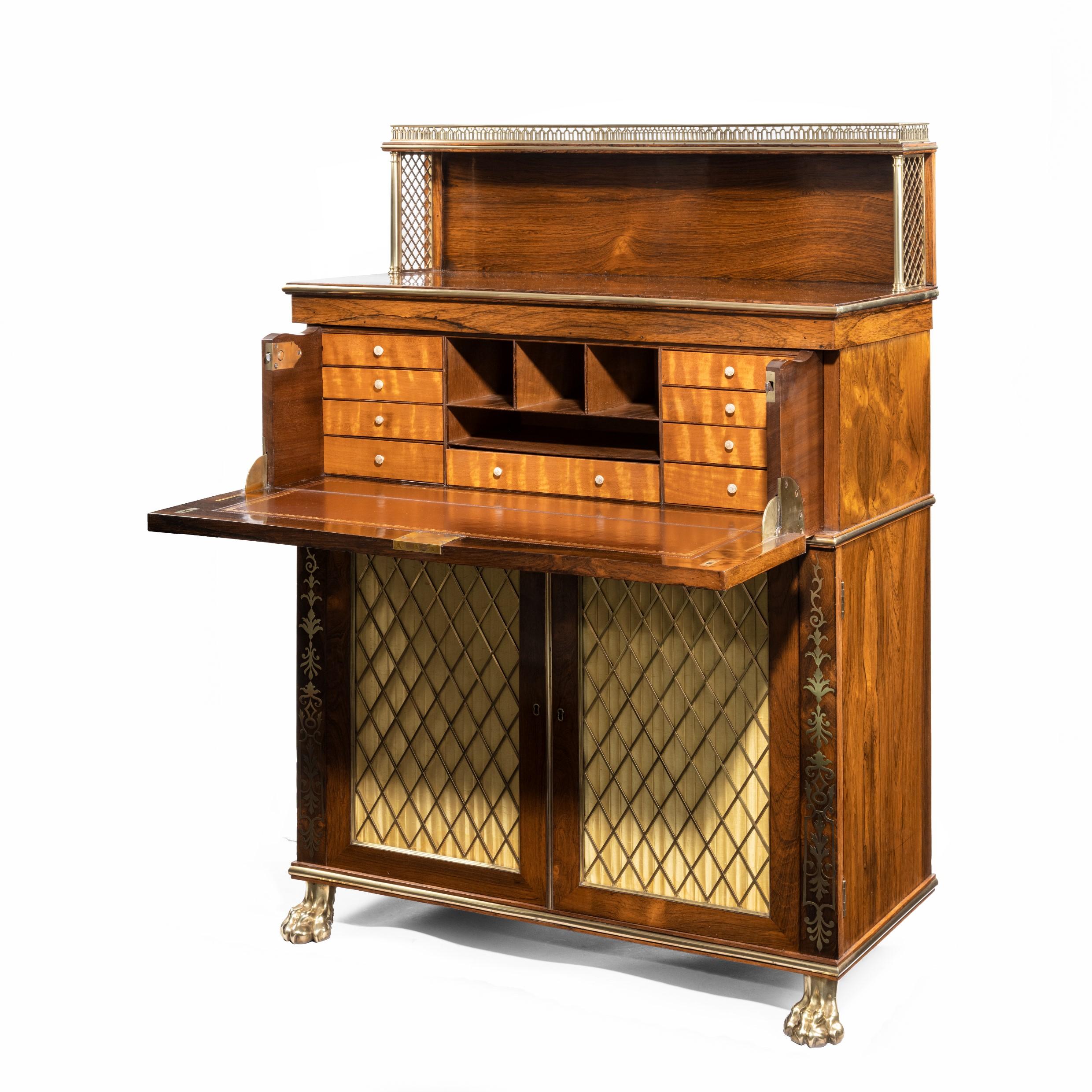 A Regency brass-inlaid rosewood secretaire cabinet, the rectangular top with a pierced galleried shelf with trellis work on the sides, above a secretaire drawer, banded with brass palm leaves on an ebony ground, enclosing nine satinwood shelves