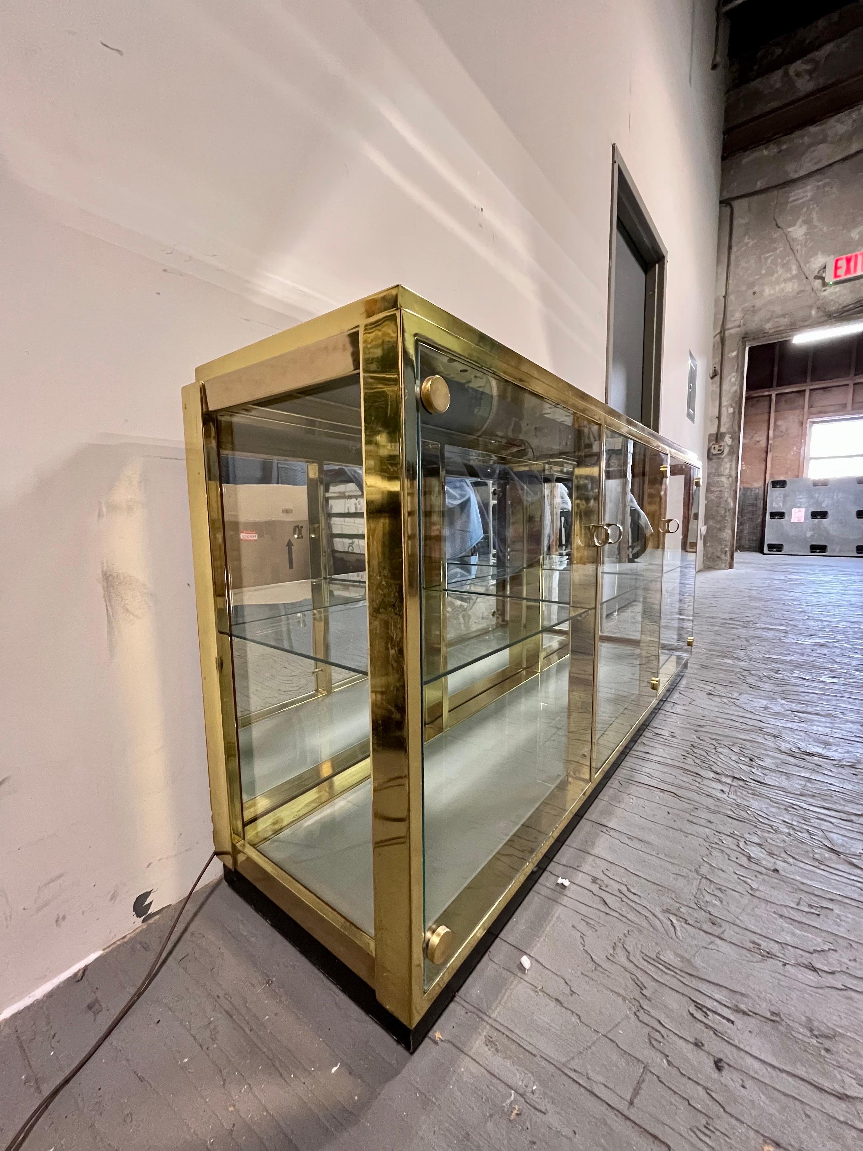 The perfect home for a vast collection of personal treasures. This Regency display case is framed with patinated brass and faced with several panels of glass to show off its interior, topped with a beautiful piece of bevelled mirror. The case is