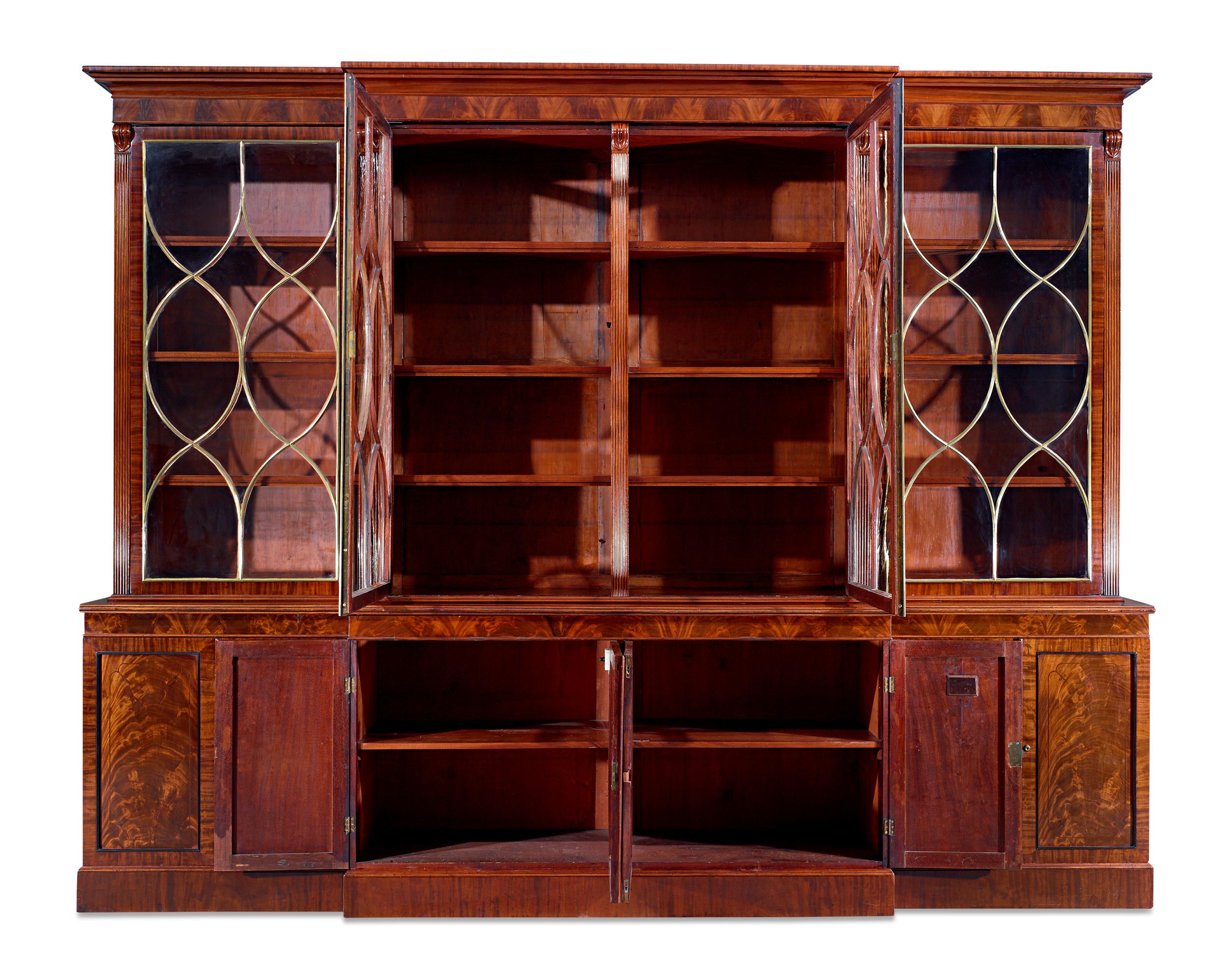 This incredibly rare Regency breakfront bookcase exhibits the superior caliber most closely attributed to the famed Gillows of Lancaster. Measuring over 11-feet wide, this monumental cabinetry masterpiece combines luxurious materials with the expert
