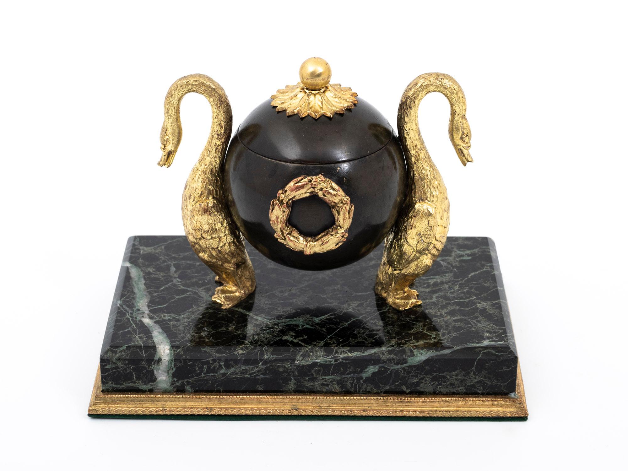 A beautiful Regency bronze gilded Inkwell standing on a green marble base.

An elegant green marble base supports this stunning Regency Inkwell, which boasts unique features such as a spherical design exquisitely adorned with two gilt swans; an