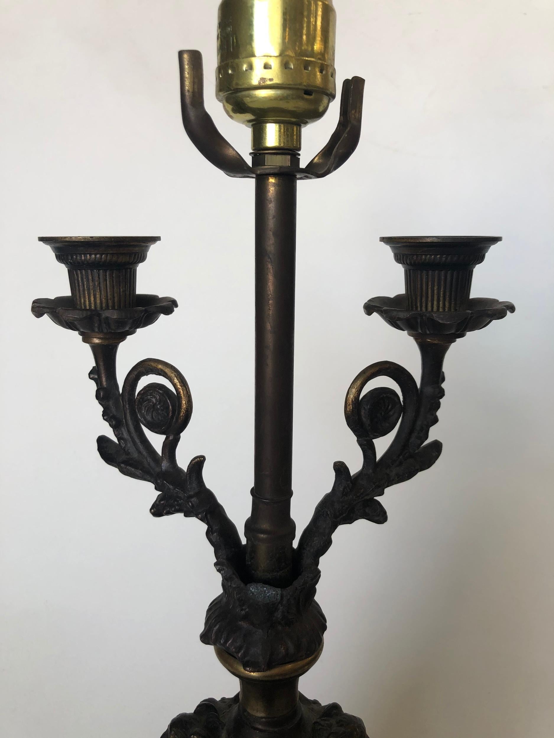 Regency bronze cherub candelabra table lamp featuring a single light socket and two candleholders.

Measures: 19