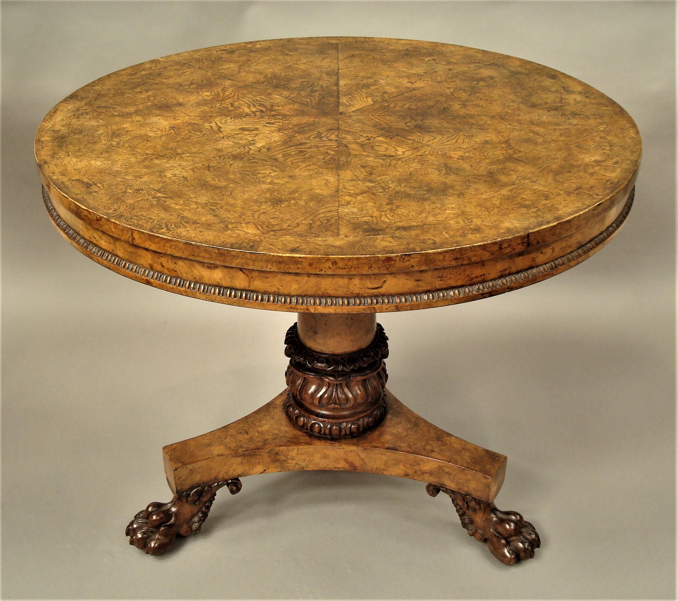 A good late Regency burr ash, elm and oak centre table; the circular tilting top with striking well figured burr ash veneers in a segmented radiating design with a wide cross banded border; above an inset frieze with a gadrooned moulded edge; raised