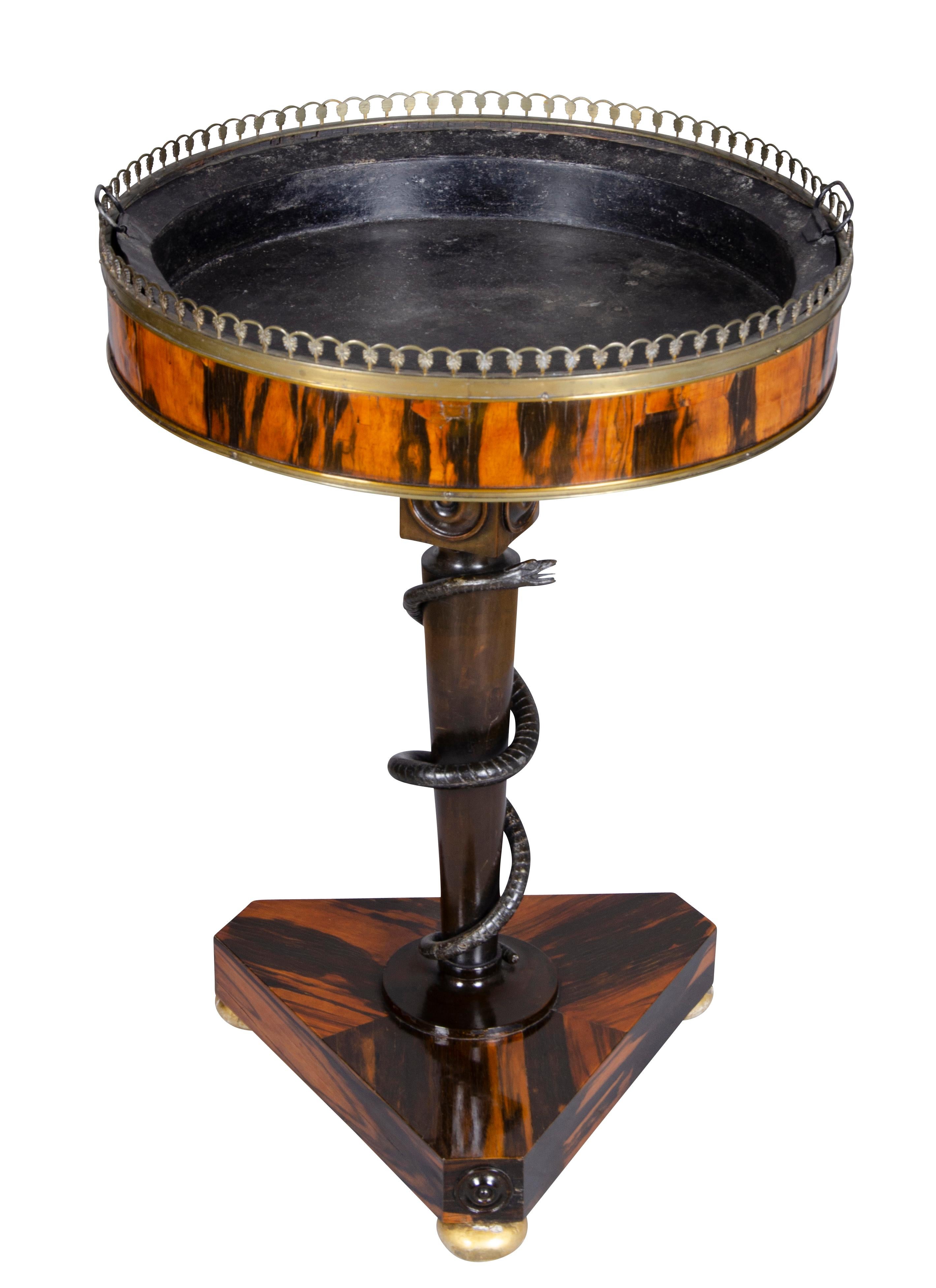 Circular bowl with tin lining and brass border raised on a columnar support with a carved snake wrapped around, tripartite base with gilded bun feet.