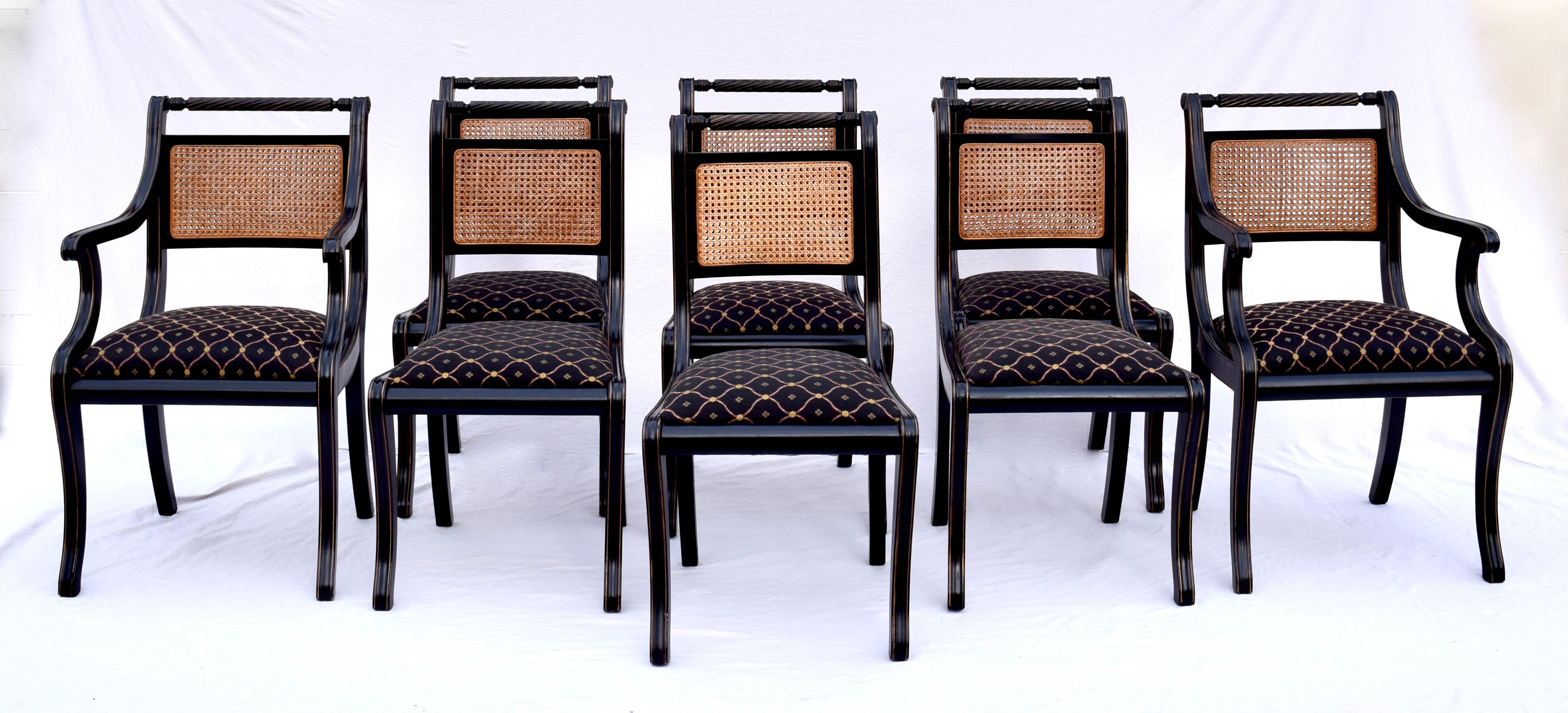 Set of eight English Regency style dining chairs feature solid lacquered wood construction with rope twist horizontal crests having substantial double caned back and front detailing. Upholstered seats raised on Klismos legs with gold gilt accents