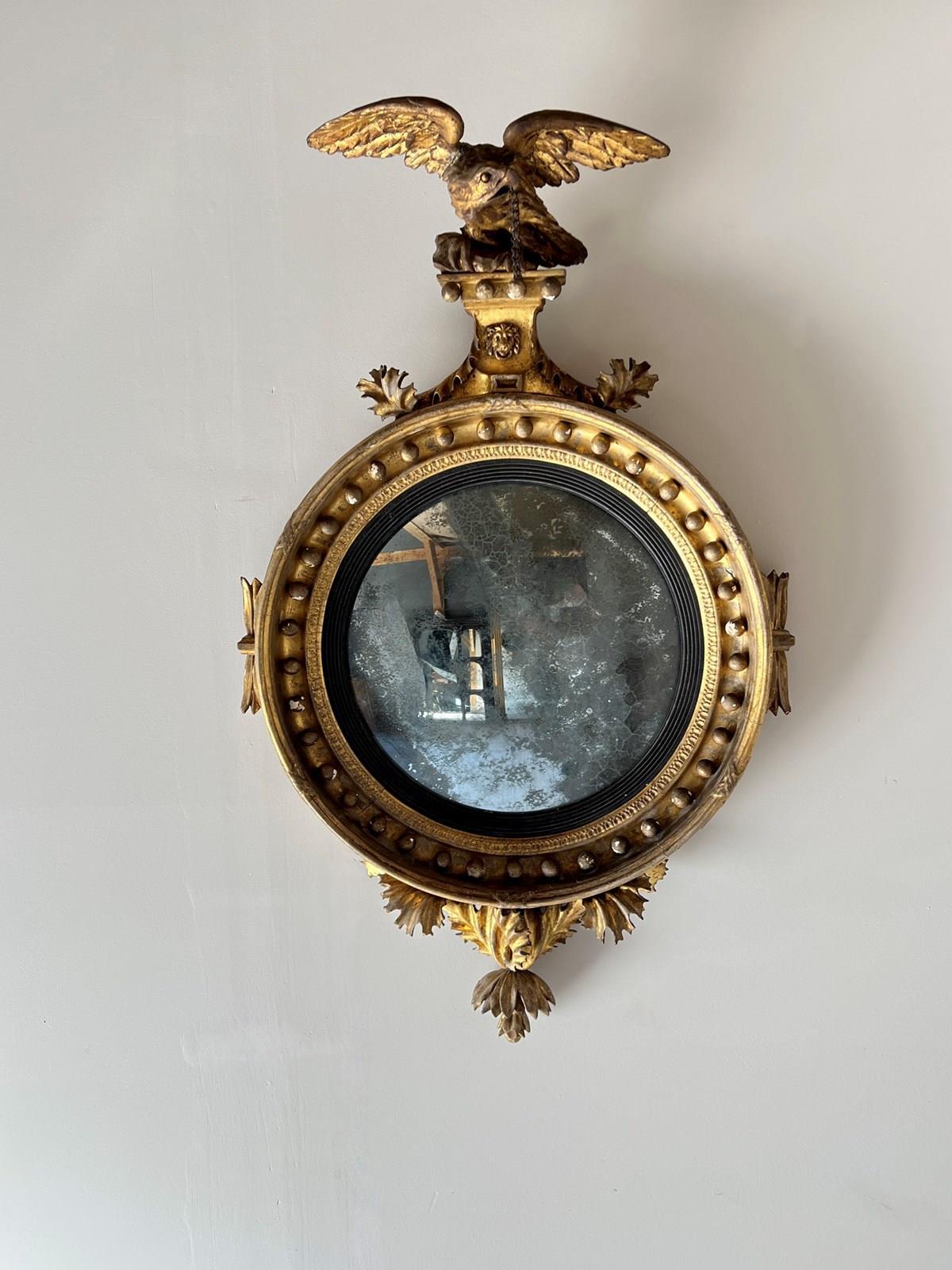 A Fine Example of a Regency Carved Giltwood and Gesso Convex Wall Mirror. Rare to find of this quality in its original unrestored condition. The pediment surmounted with a finely carved eagle with lions mask below. Flanked by finely carved leaf
