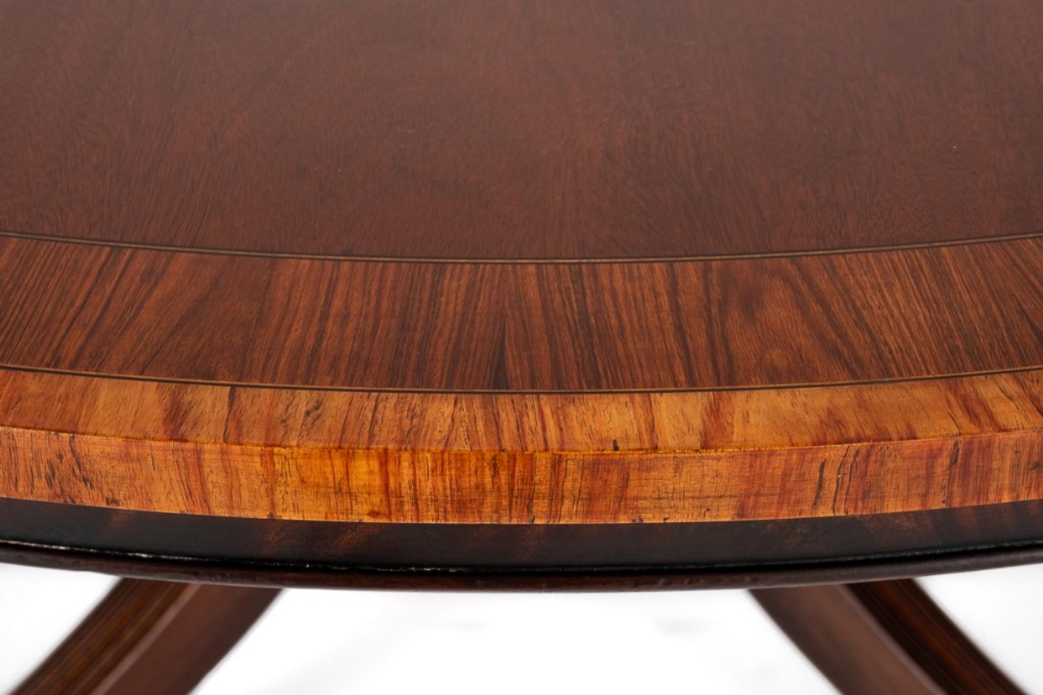 Regency Revival mahogany Centre Table.
This Centre Table is raised Upon a turned Centre Column With Shaped and Fluted Largs Terminating in Brass Box Castors.
The Top of The Table Features A Double Cross-banding of Rosewood and Kingwood.
Circa