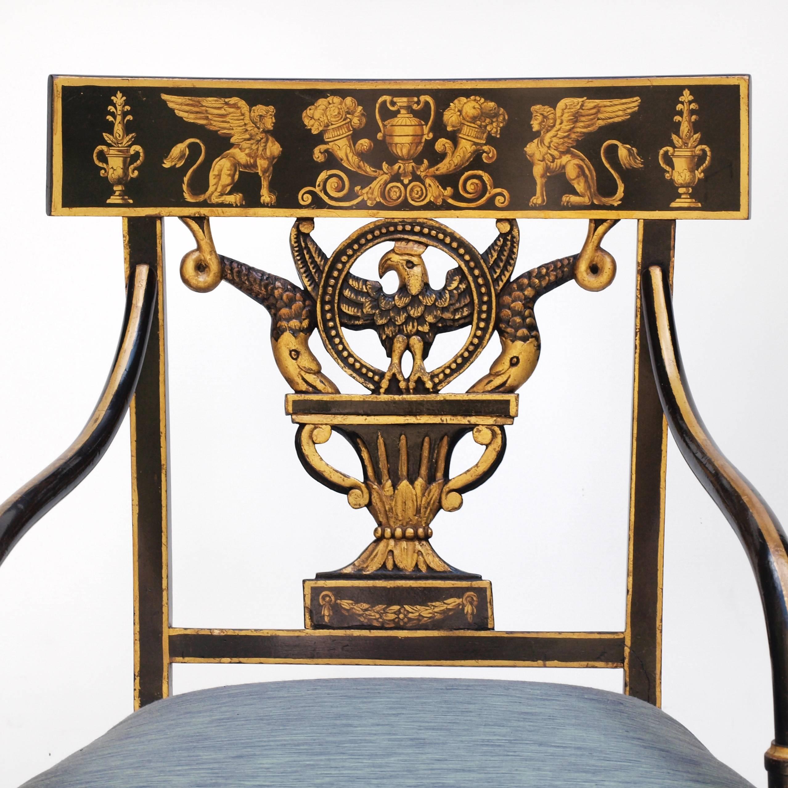 An early 19th century American armchair. The chair is designed in a regency style with a curved tablet back and open carving leading to gently sloping legs. Bentwood arms connect the back to the front legs, supporting a wide upholstered seat. The