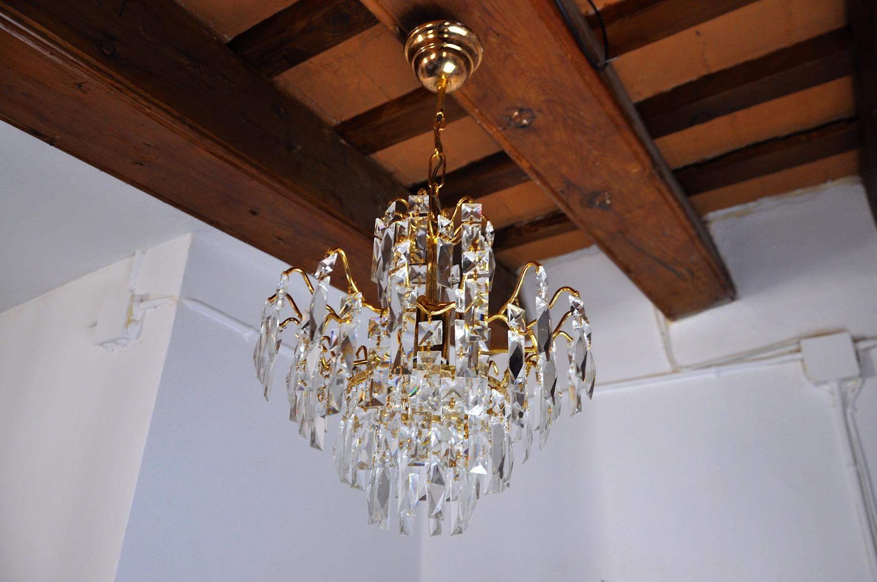 Bellissimo lampadario hollywood regency risalente agli anni '80. Questo lampadario è realizzato con cristalli di rocca tagliati e una struttura in metallo dorato. Un oggetto dal design unico che illuminerà meravigliosamente i tuoi interni.