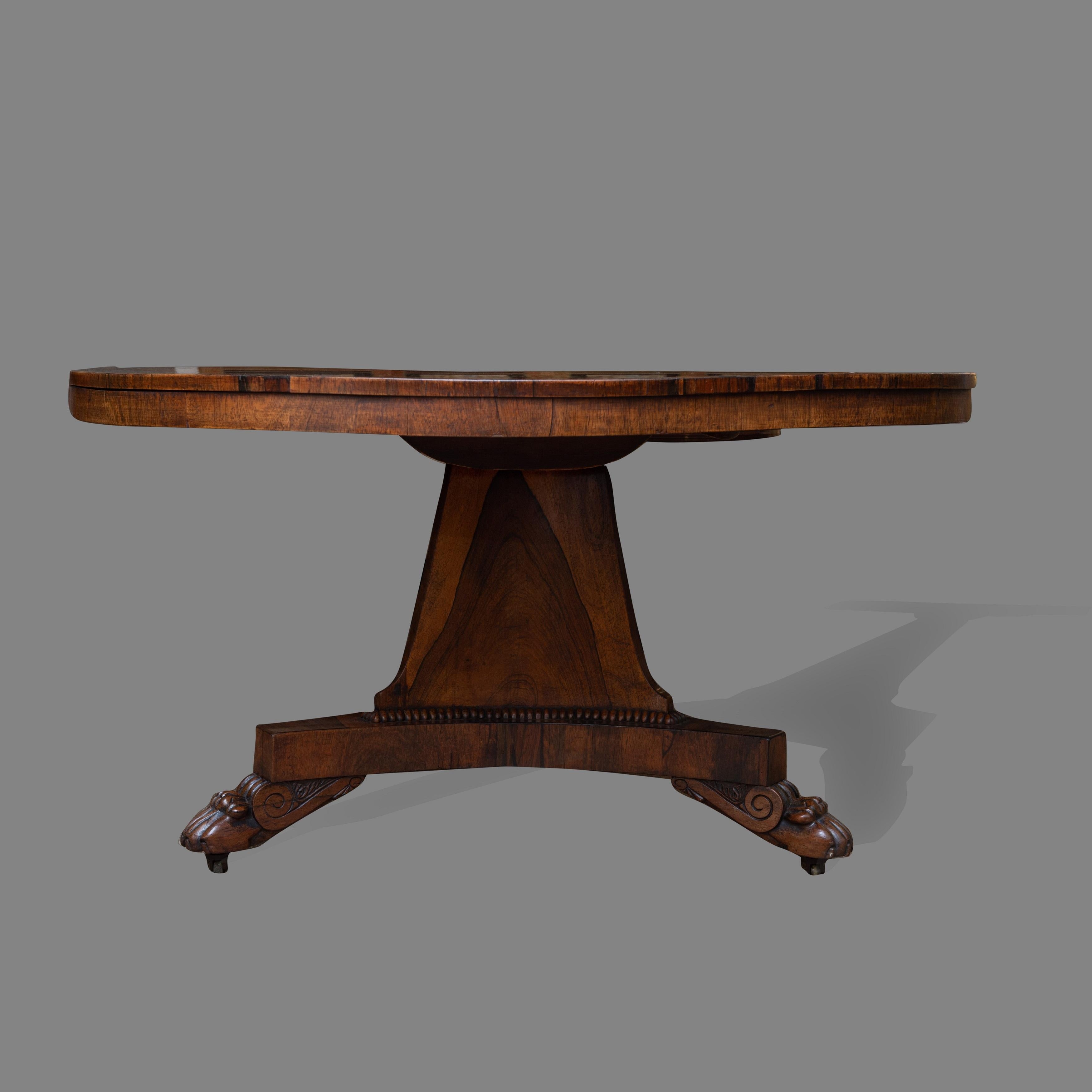 Of excellent color and condition. The well figured rosewood top with wide brass inlaid border of stylized foliate decoration. The central triform column support with rich molding adjoining a conforming triform terminating in well carved claw feet on