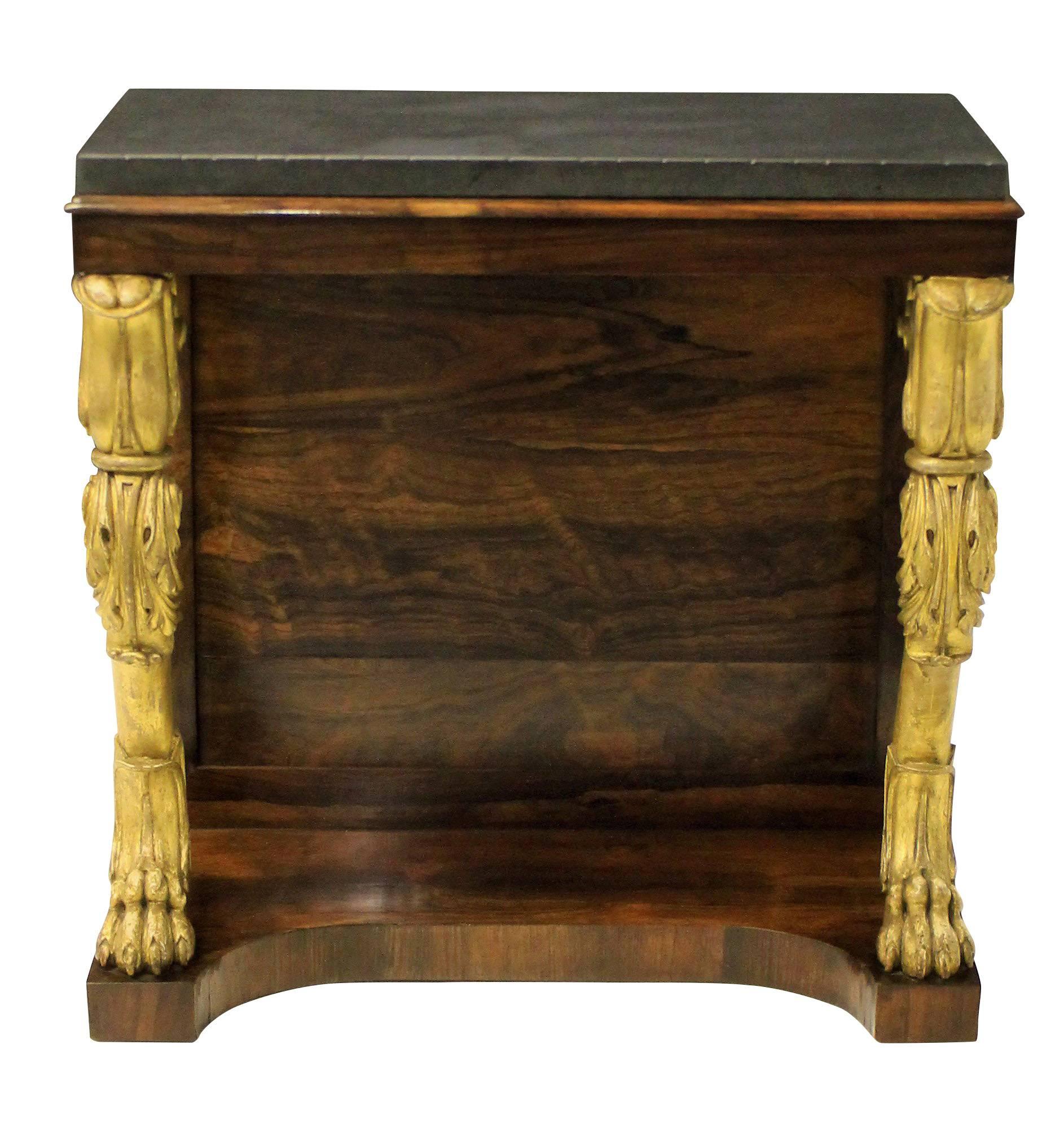 An English Regency console table in rosewood, with two carved and water gilded monopodia legs. The top of Belgian marble.

