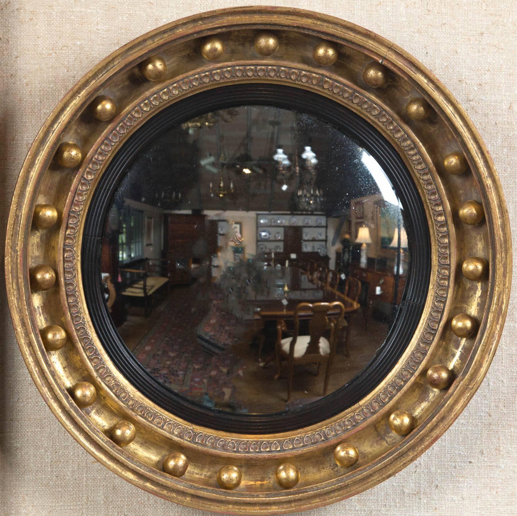 Fine example of a petite Regency convex giltwood mirror with egg and dart surround and ebonized slip. Original glass.