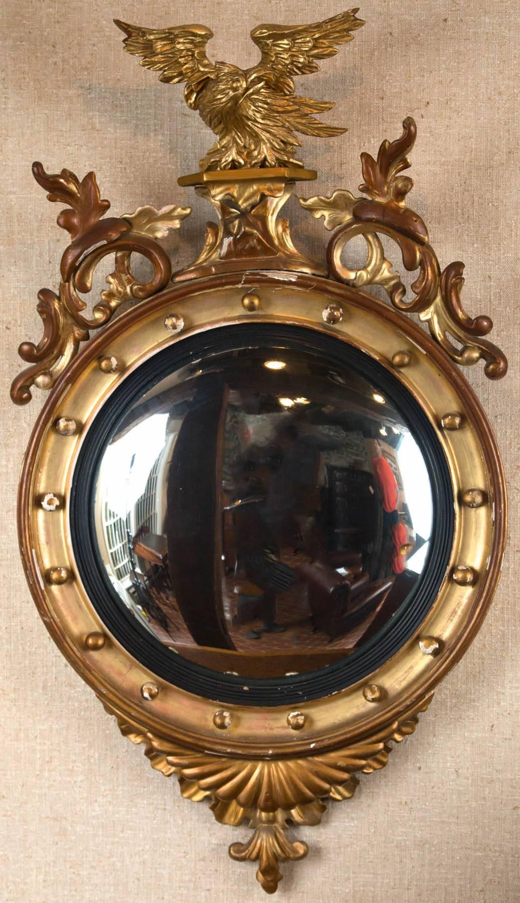 English giltwood convex mirror with reeded ebonized slip and surmounted with well carved eagle with scroll supports. Original glass and gilt.