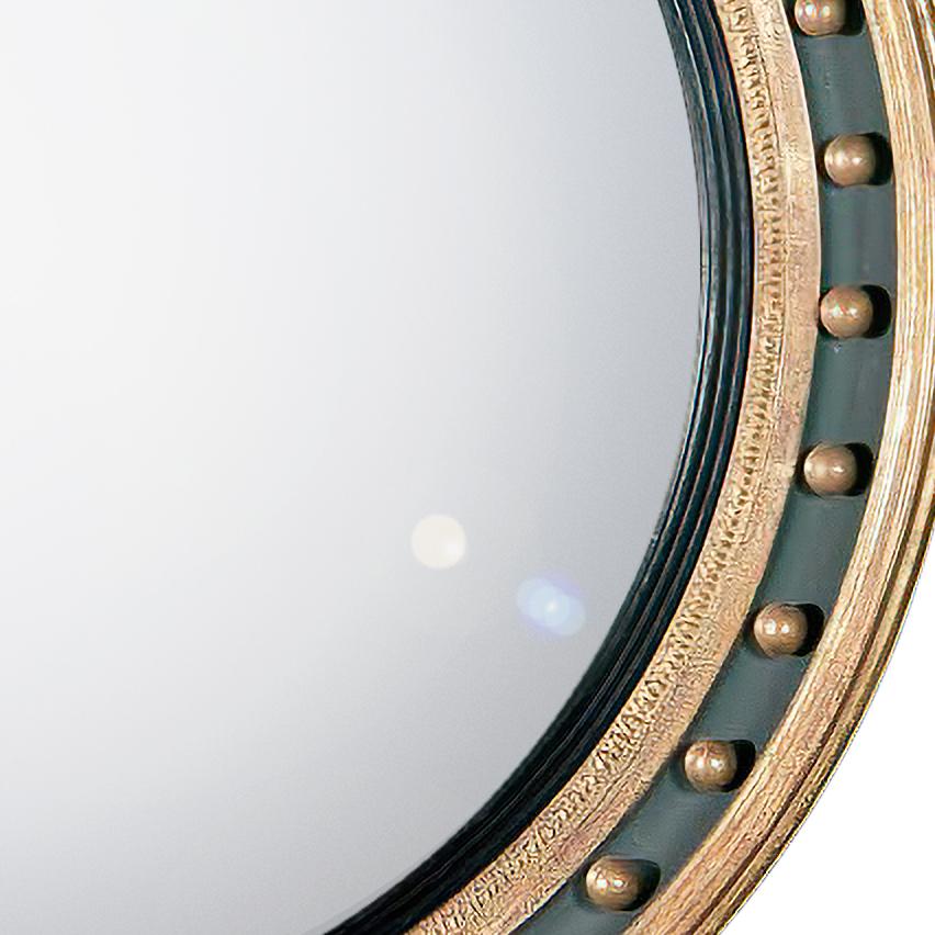 Dieser schlichte, geschnitzte, vergoldete und ebonisierte, konvexe Spiegel hat einen geformten Innenrahmen und einen zusammengesetzten, geformten Außenrahmen mit dekorativen, vergoldeten Kugeln, die den gemalten Grund unterstreichen.
Maße: 39,5