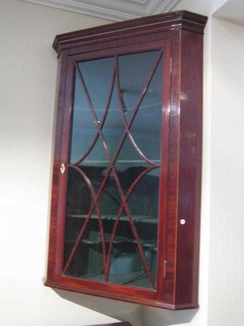 Sn884 Fine quality, Regency, mahogany, glazed corner cupboard, having moulded cornice with ebony and satinwood string inlay, astragal glazed door with ivory escutcheon, enclosing 4 shelves, satinwood string inlay to either side of door, all in