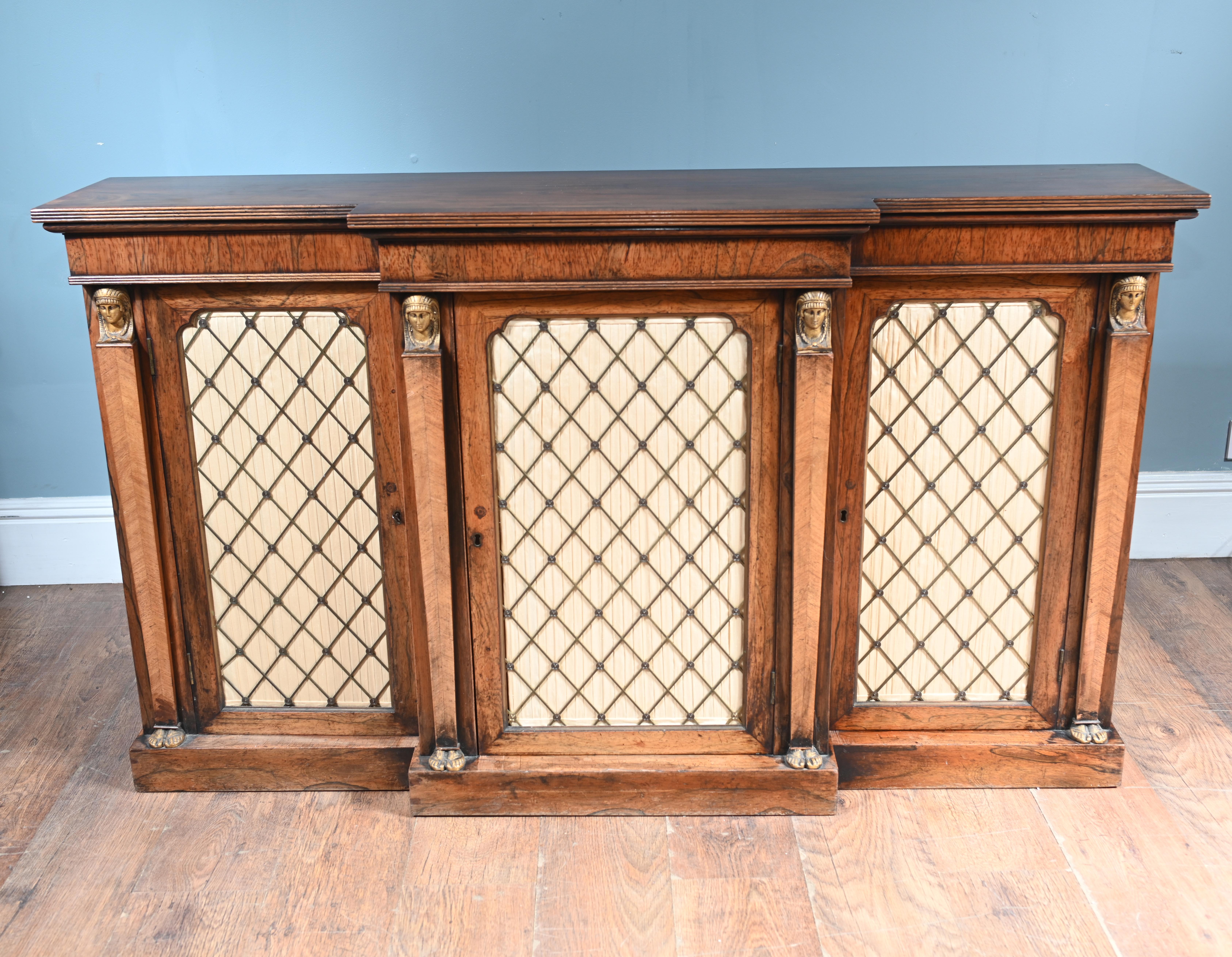 Period Regency credenza or side cabinet of breakfront form
The three front doors are inset with decorative brass grilles over pleated cream silk panels in a diamond lattice design – a classic Regency feature
The vertical stiles are embellished with