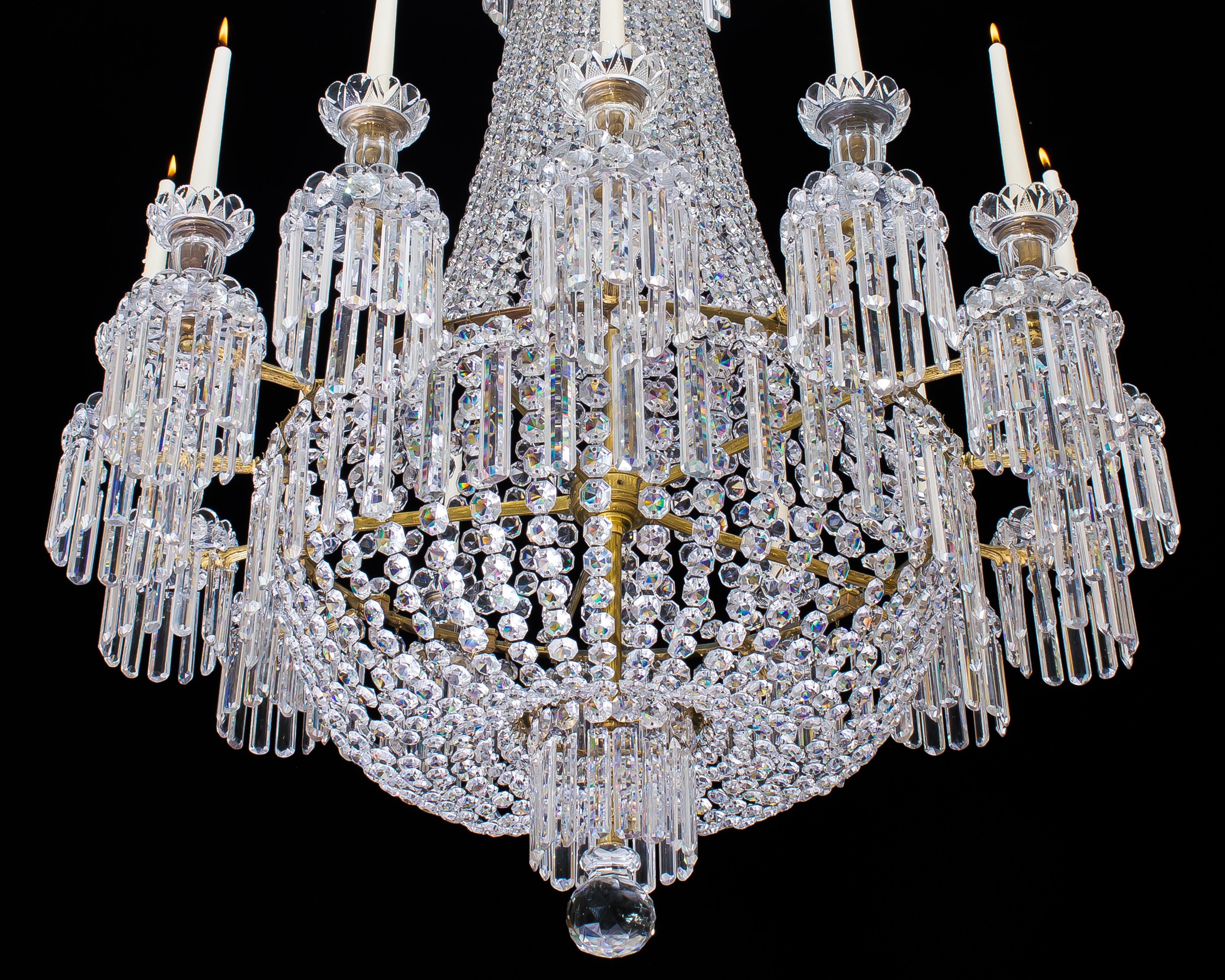 A fine gilt bronzed and cut crystal Regency chandelier of Classic tent and basket design the upper tiers formed of three graduated drop hung rings with tent chains cascading to the main band, issuing fourteen finely cast candle branches these