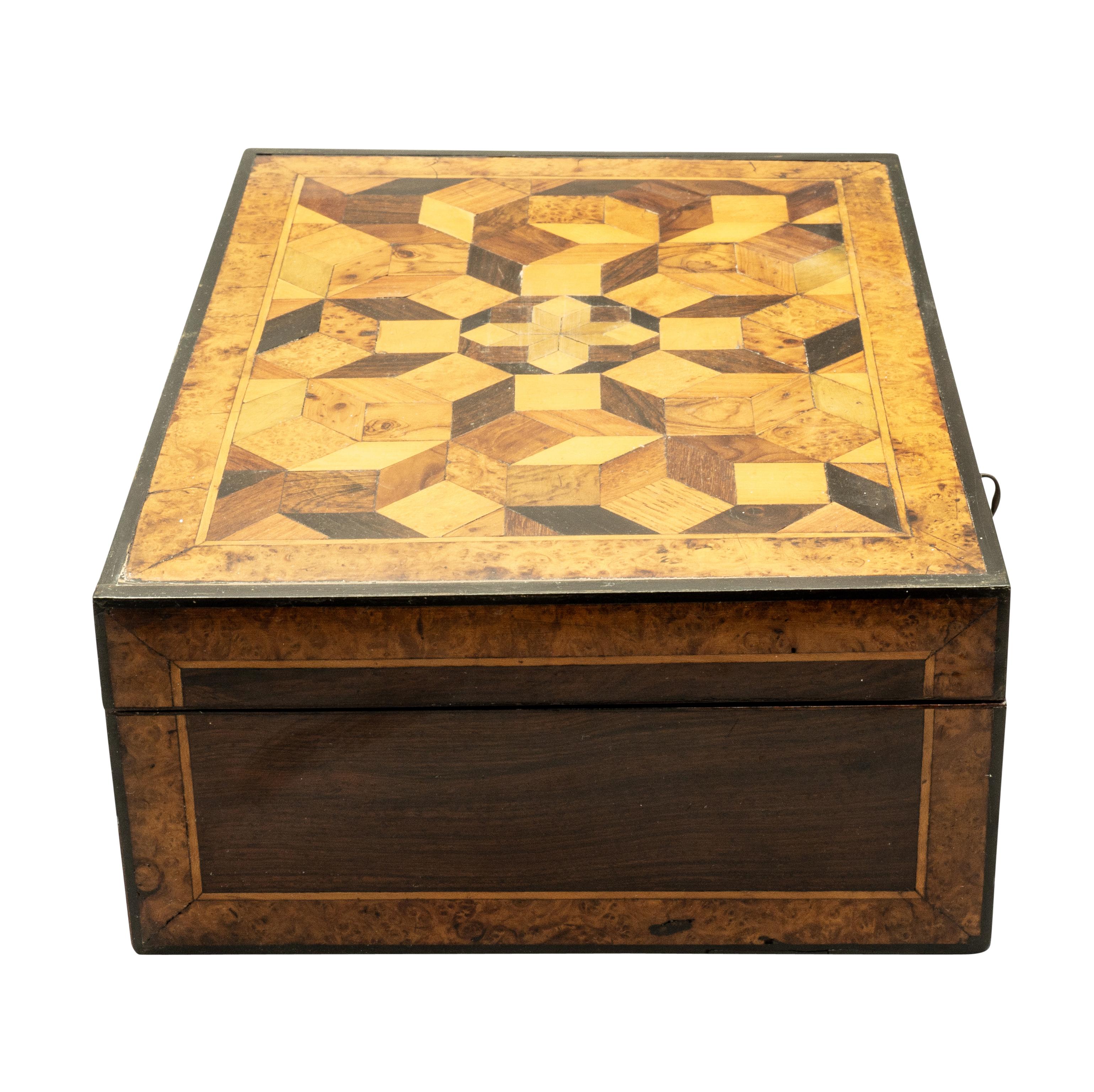 Rectangular with hinged lid featuring beautifully laid out design of cube parquetry. Fitted interior. Conforming case. 