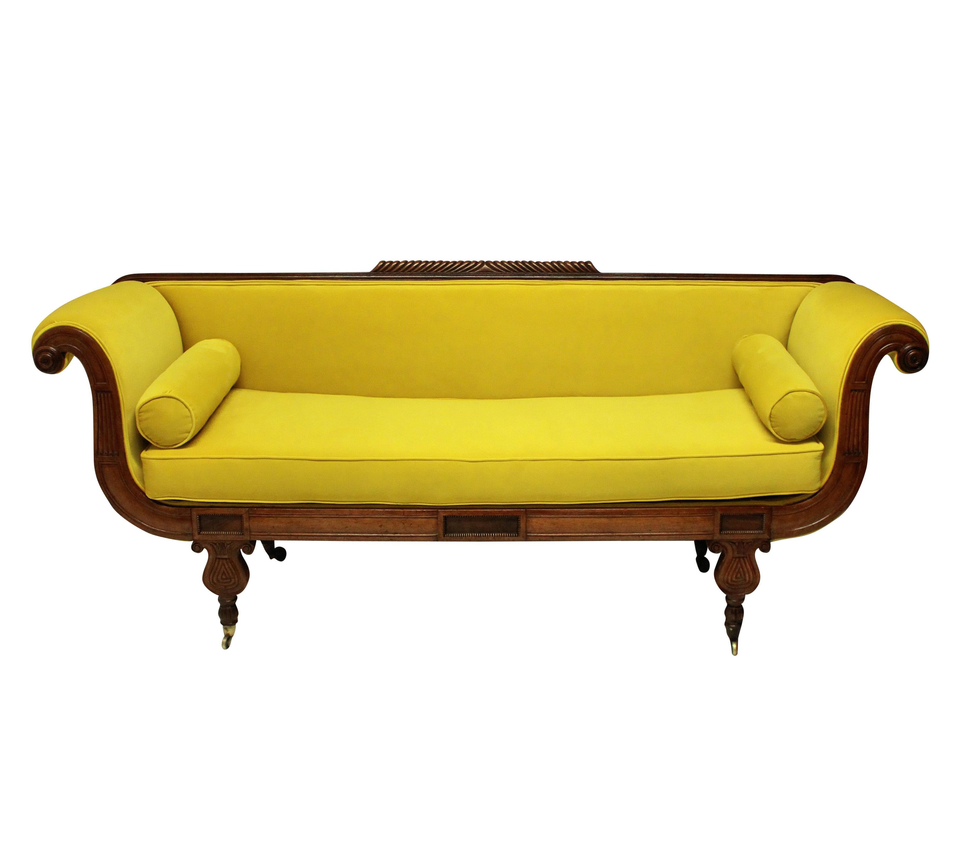 An English Regency daybed, of neoclassical design in crisply carved mahogany and newly upholstered in chartreuse velvet.