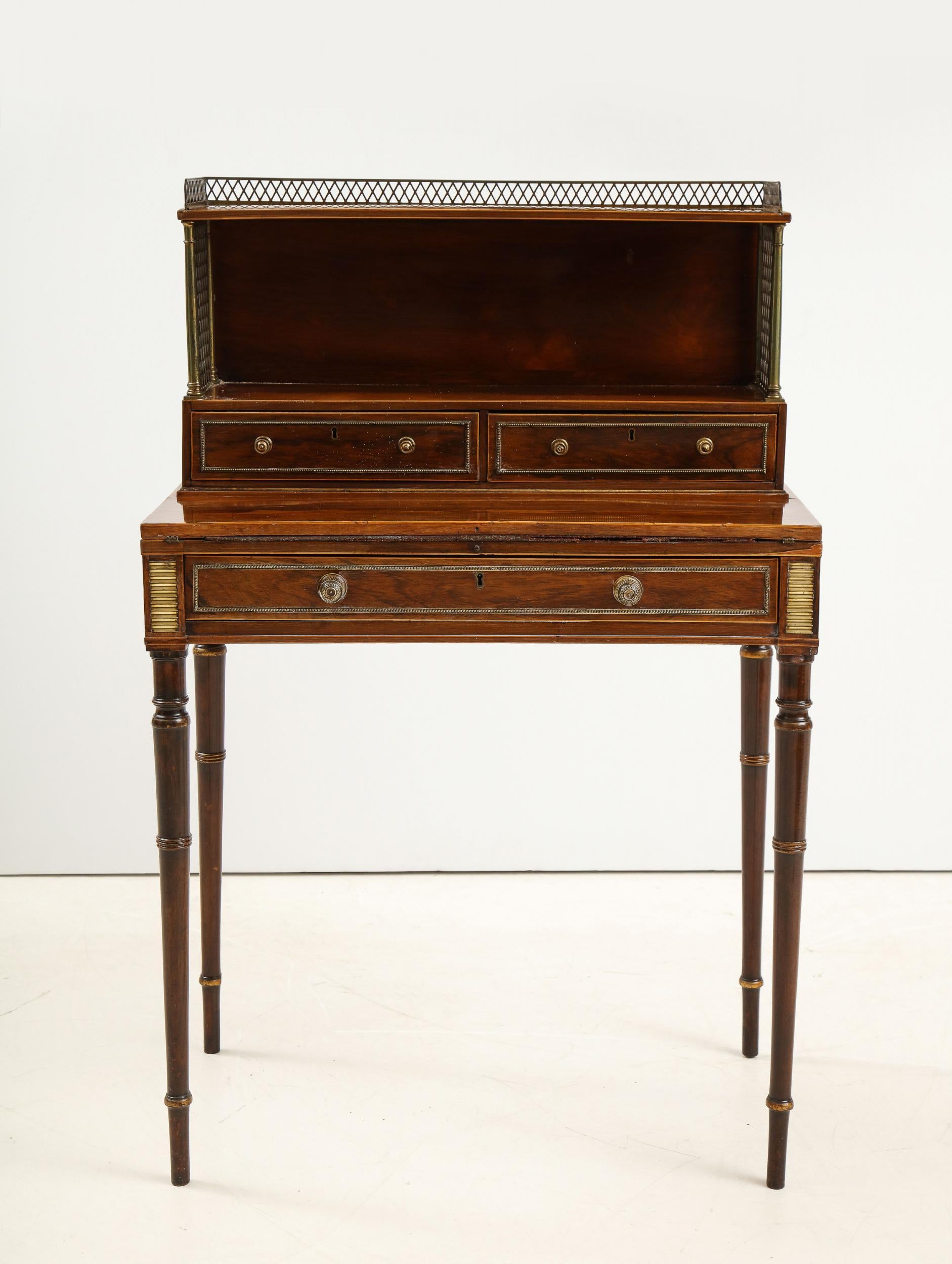 Very fine English Regency period bonheur du jour attributed to John McLean & Son, the rectangular top having pierced gallery with turned and ring collared brass column supports with pierced diamond pattern panels of gilt-brass above a shelf fitted