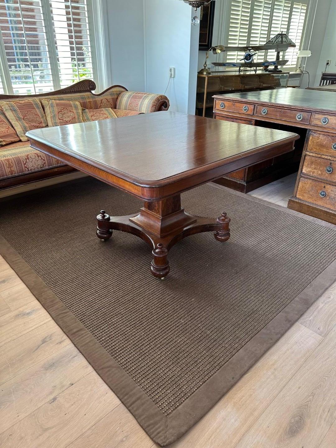 Antique mahogany dining room table on sleek column leg. Beautiful table from the Regency period. Table is in good condition and very stable. Top has signs of wear and leg has old imperfections. The square shape has a distinguished appearance.
