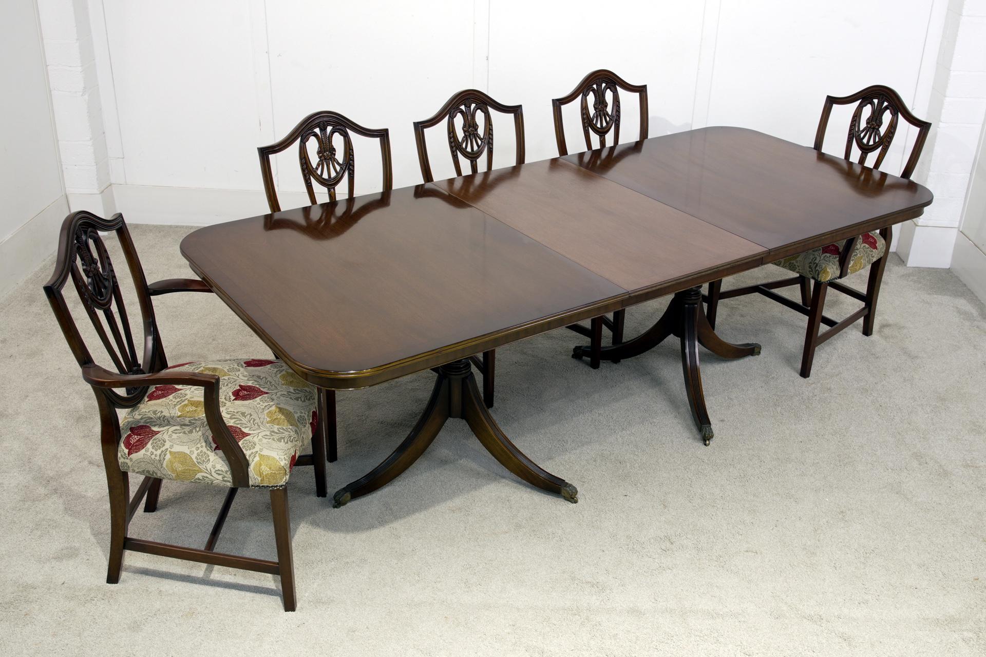 You are viewing an elegant Regency style dining table and matching Hepplewhite chairs
The table top has softly rounded corners and includes a central extension leaf for additional seating capacity
The twin pedestal bases rest on splayed legs with