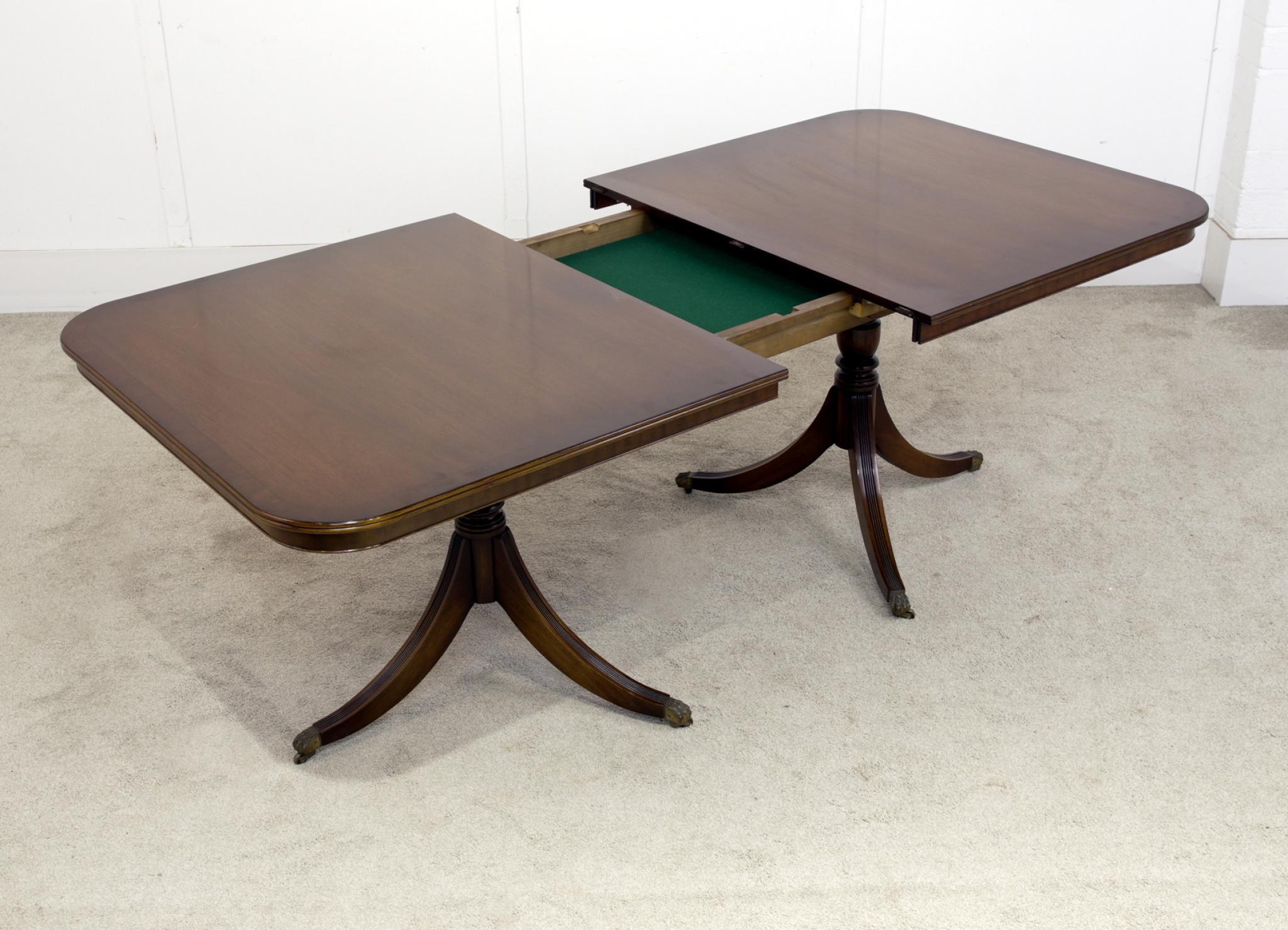 You are viewing an elegant Regency Revival dining table with matching set of 8 chairs
The table features a gently rounded rectangular top with a rich mahogany finish, supported on elegant turned legs that terminate on brass castors — a classic