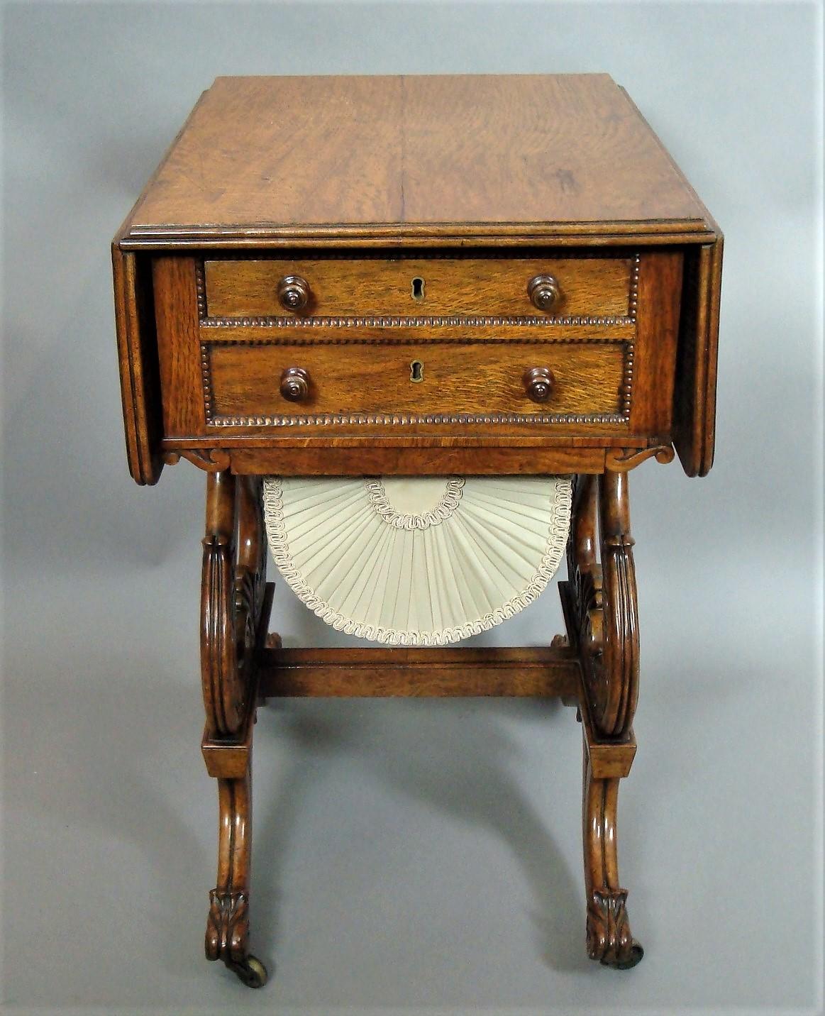 Late Regency pollard oak drop-flap work table; the well figured rectangular top with rounded corners above opposing mahogany lined drawers, including a dummy drawer to either side; with beaded mouldings and turned knob handles; above a sliding