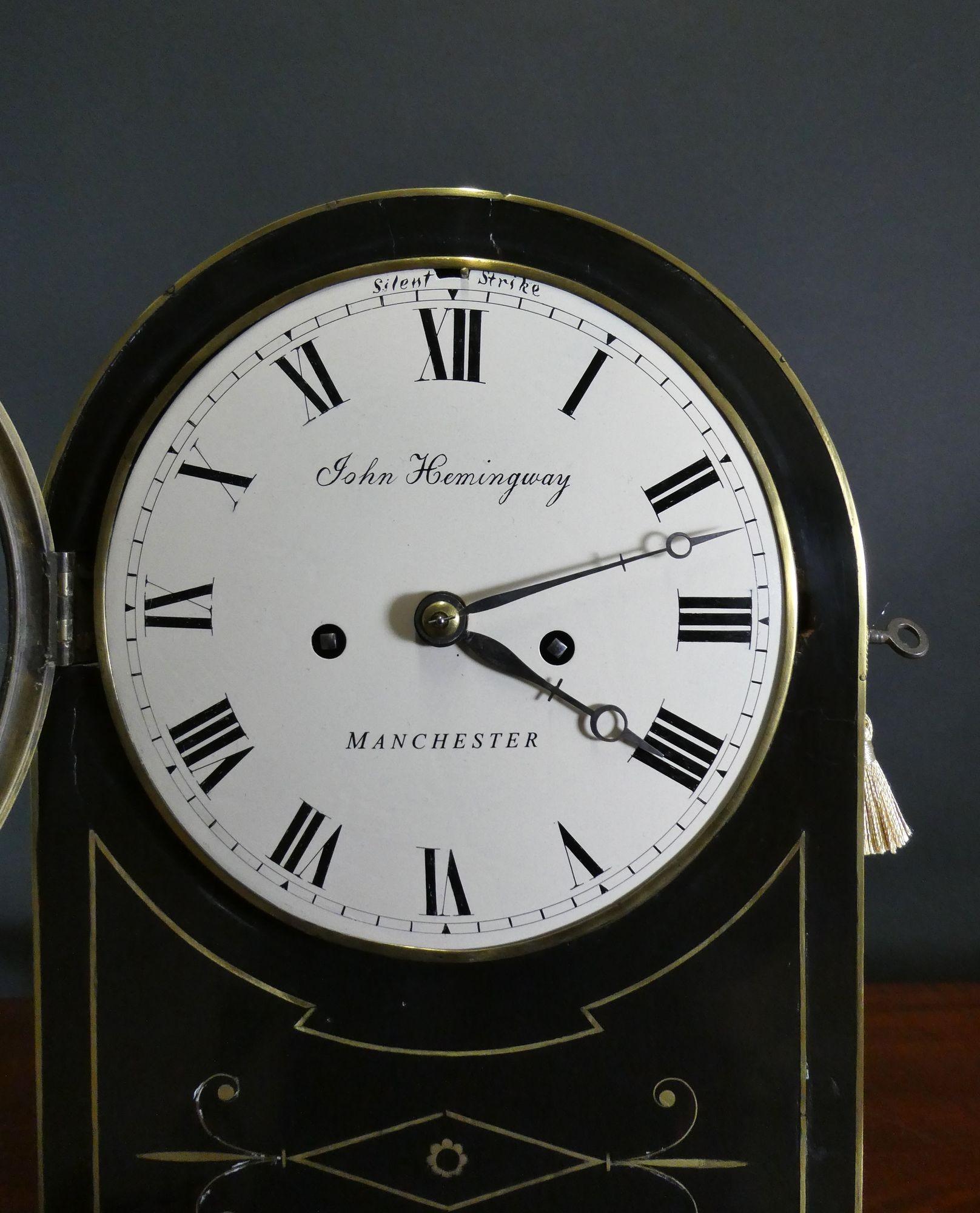 Regency Bracket Clock by John Hemingway, Manchester
Ebonised arch top bracket clock standing on a raised, moulded plinth and resting on four brass ball feet below an inset brass lined panel with line brass to the sides of the case surmounted by a