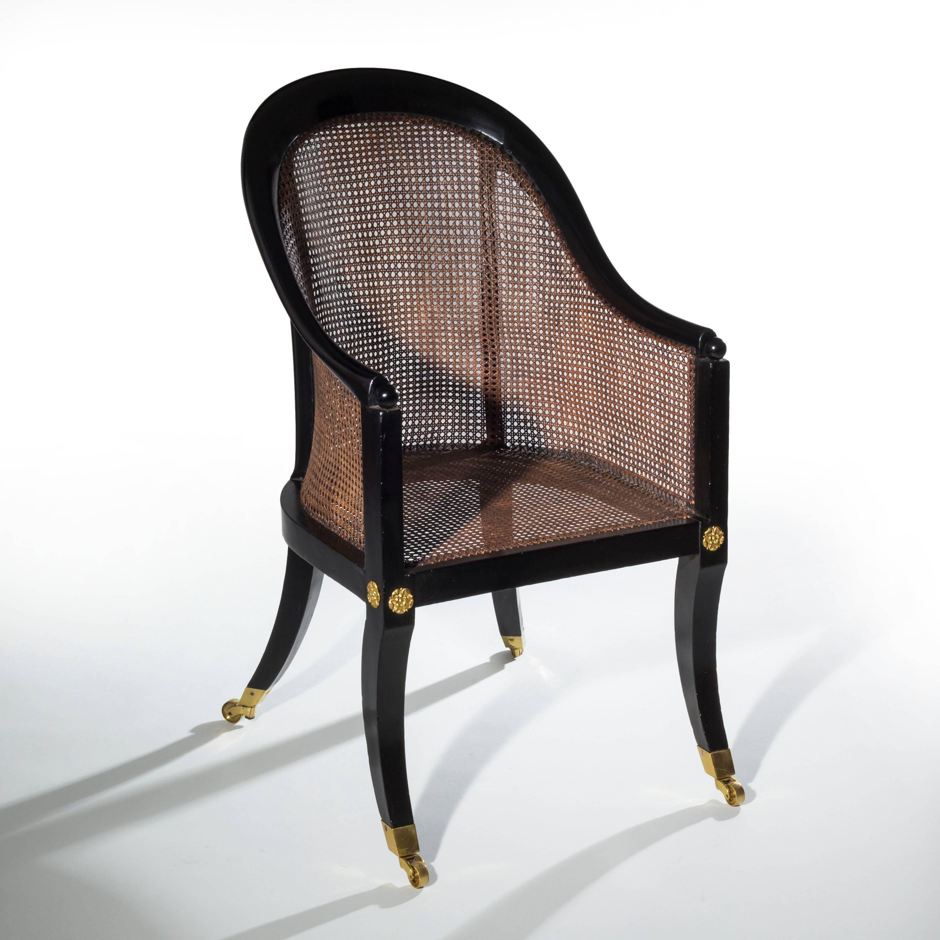 Early 19th century Regency period black lacquered (ebonized) tub bergere armchair of Grecian 'Klismos' form, attributed to Gillows of Lancaster and London. English, circa 1810

Frame caned throughout, with arched top-rail and down swept arms