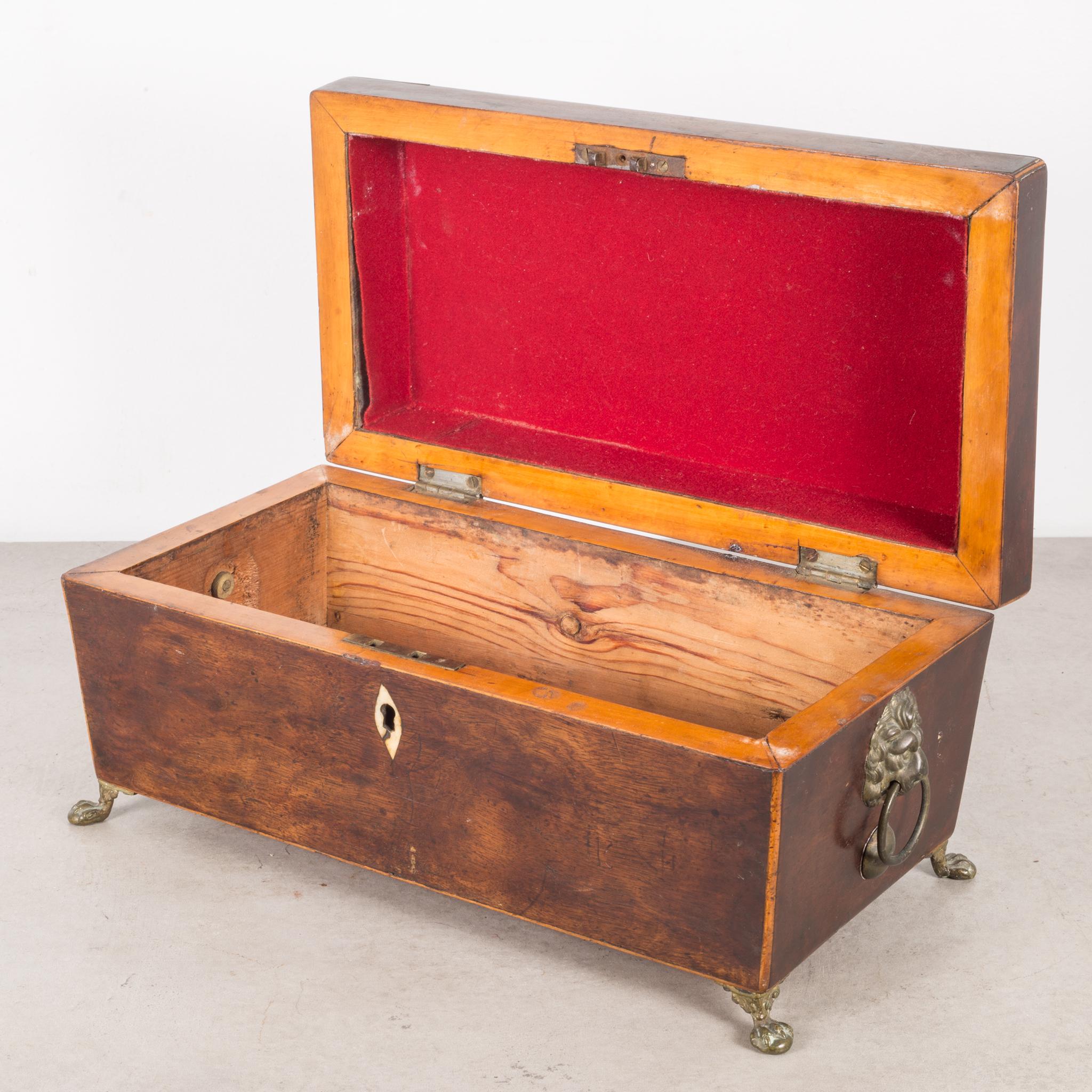 Regency (English) period rosewood sarcophagus form tea caddy,
having an inlaid bone escutcheon, brass lion head, red cloth interior and ring handles,
the whole resting on cast brass feet,
circa 1820.


  