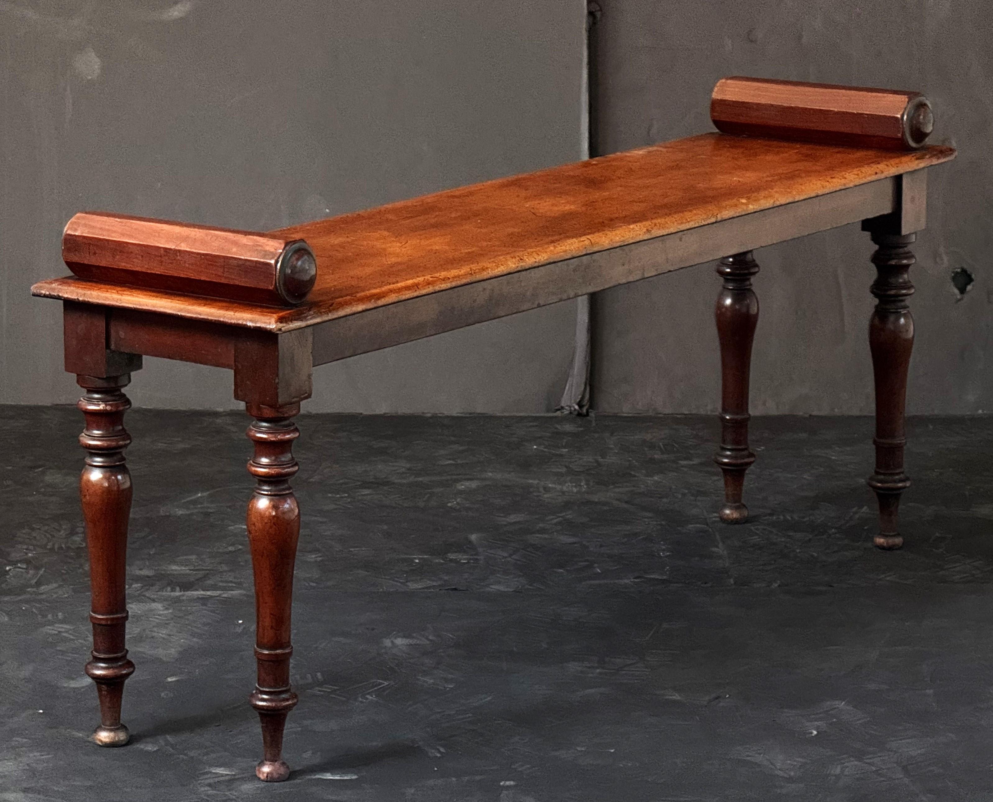 A fine English hall bench or window seat or stool of mahogany from the Regency era, featuring turned handles at opposing ends over a long plank seat and set upon four turned legs.

Dimensions:

H 20.38 inches
W 47.75 inches
D 11.75 inches

SH 18