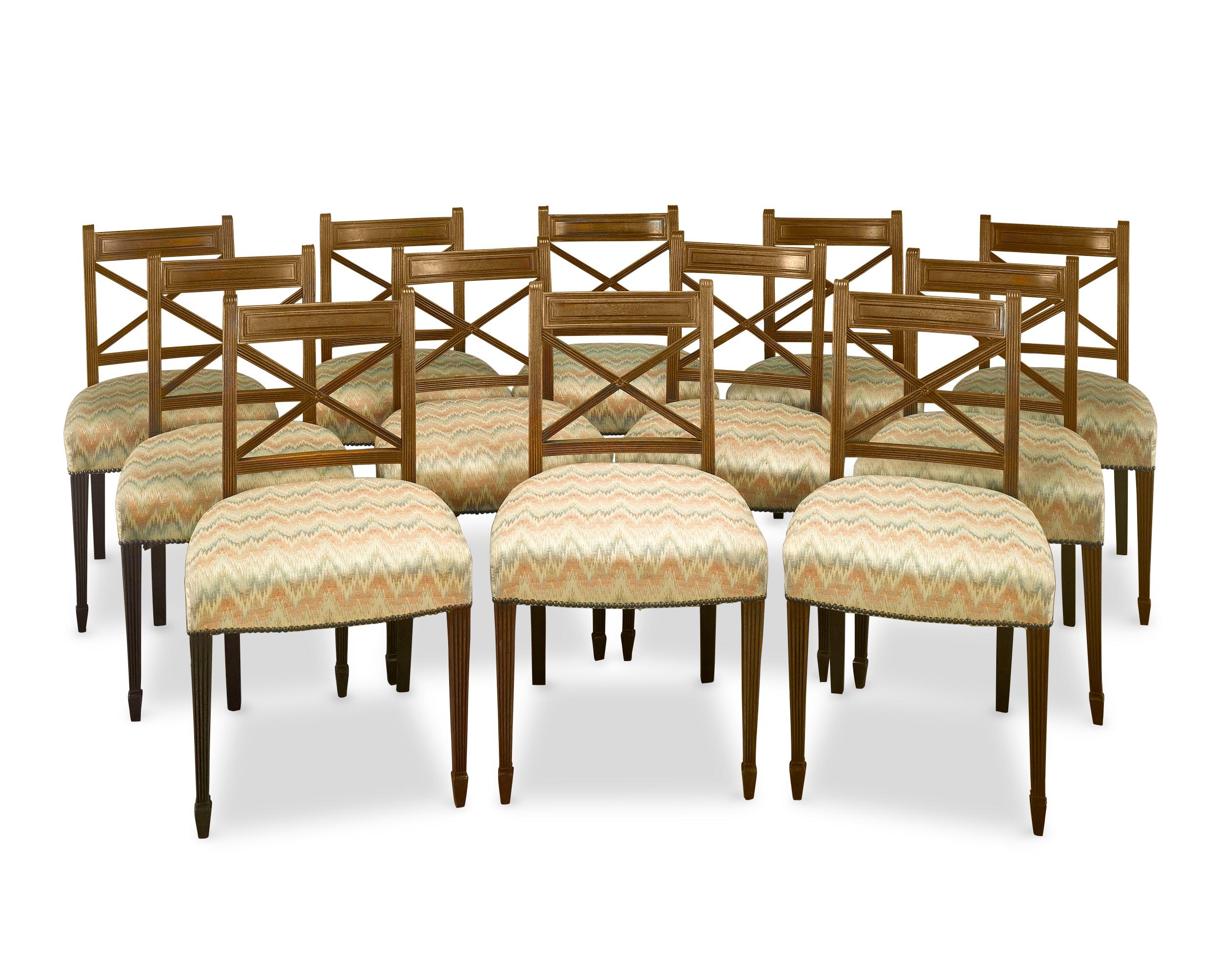 This handsome set of 12 Regency period dining chairs is and exceptional example of Regency furniture in both construction and design. The chairs are crafted of rich mahogany and are distinguished by cross-ribbon backs and saber hind legs inspired by