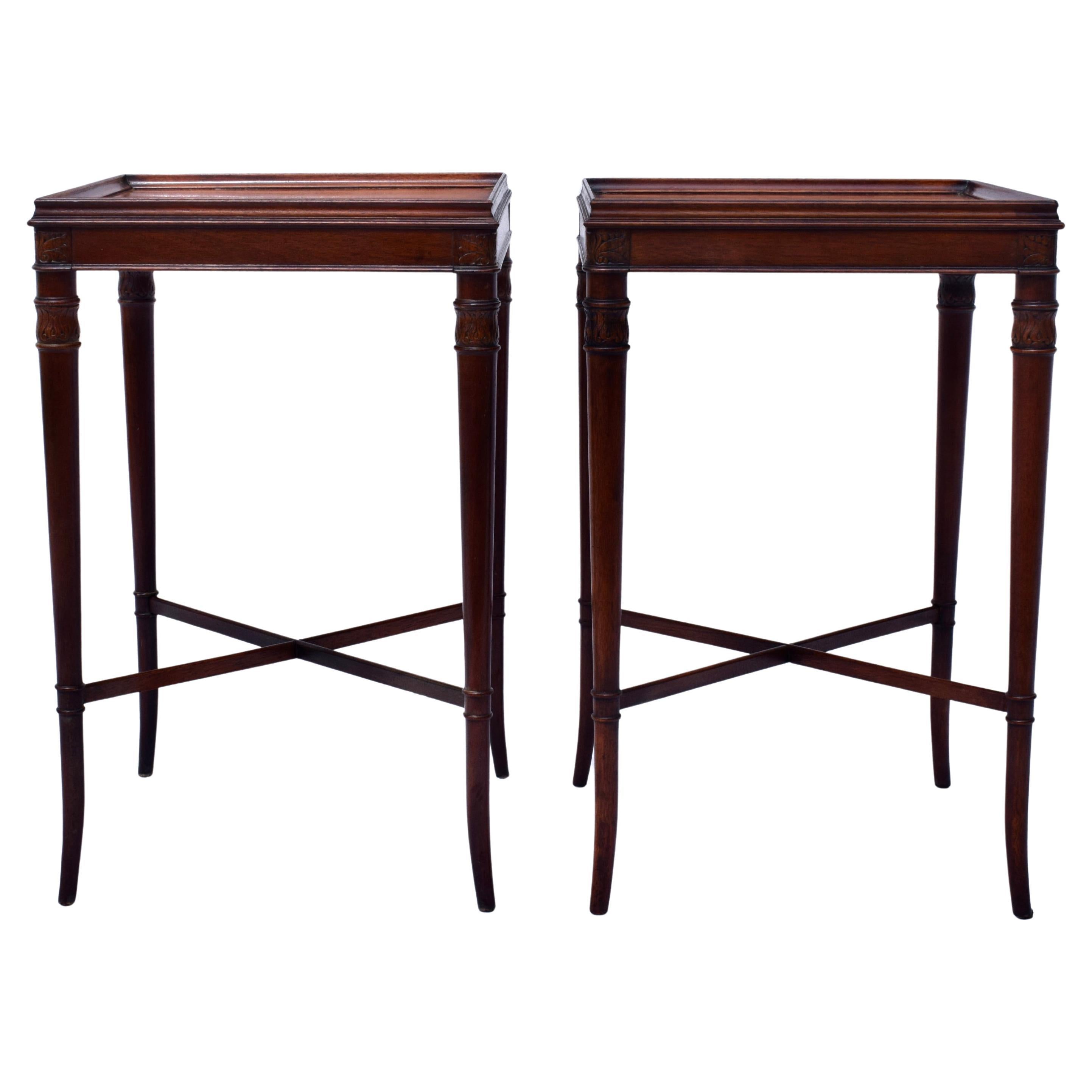 An elegant pair of vintage Regency style faux bamboo side tables of carved Mahogany with striking walnut tops,  lithe splayed legs and supporting X stretchers. Custom glass tops are included.