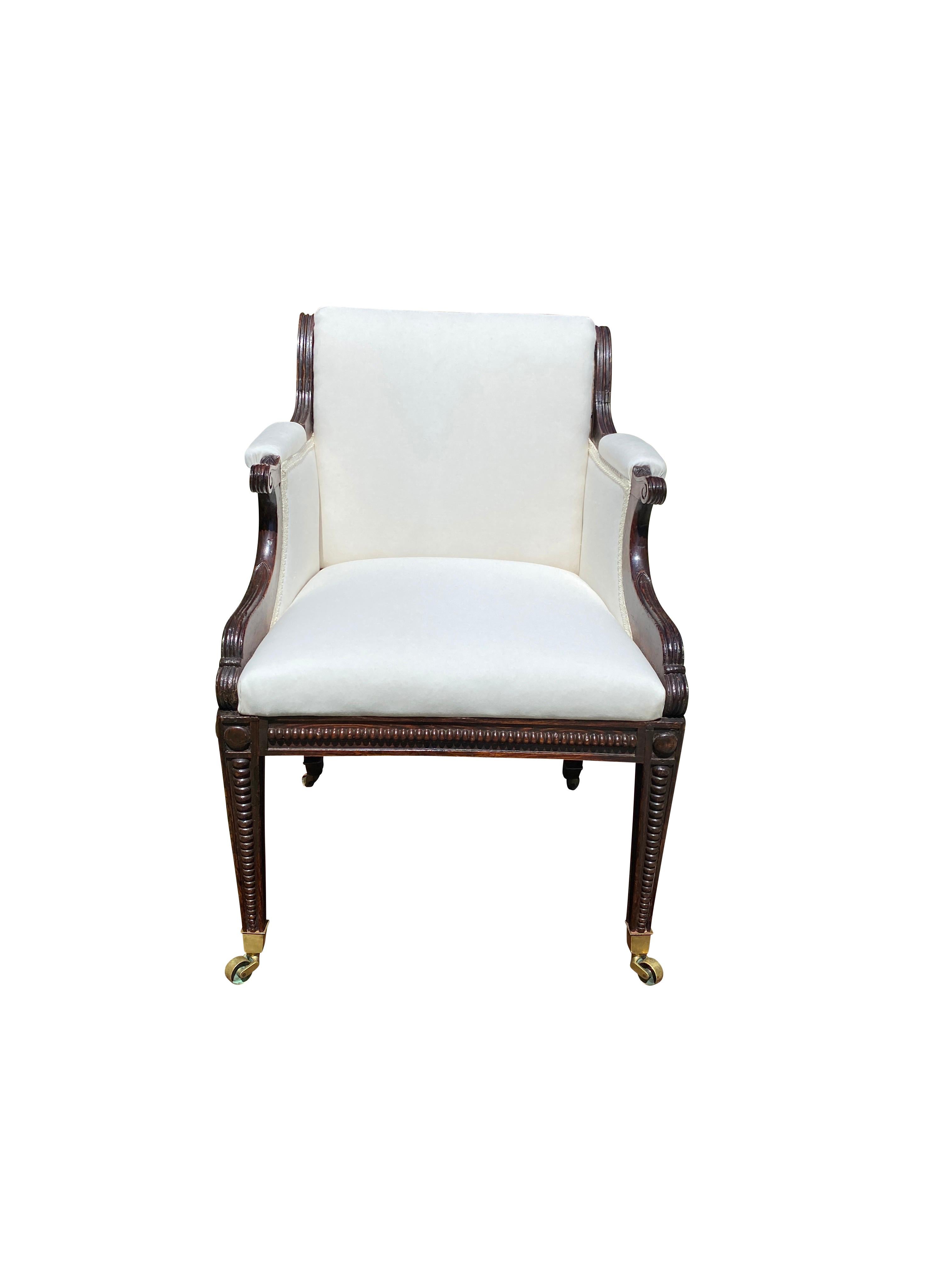 Of generous scale newly upholstered in muslin with scrolled back in the Greek revival style , nicely carved hand holds and chair frame with beaded carved decoration raised on square tapered legs with beaded carving , casters. This was designer