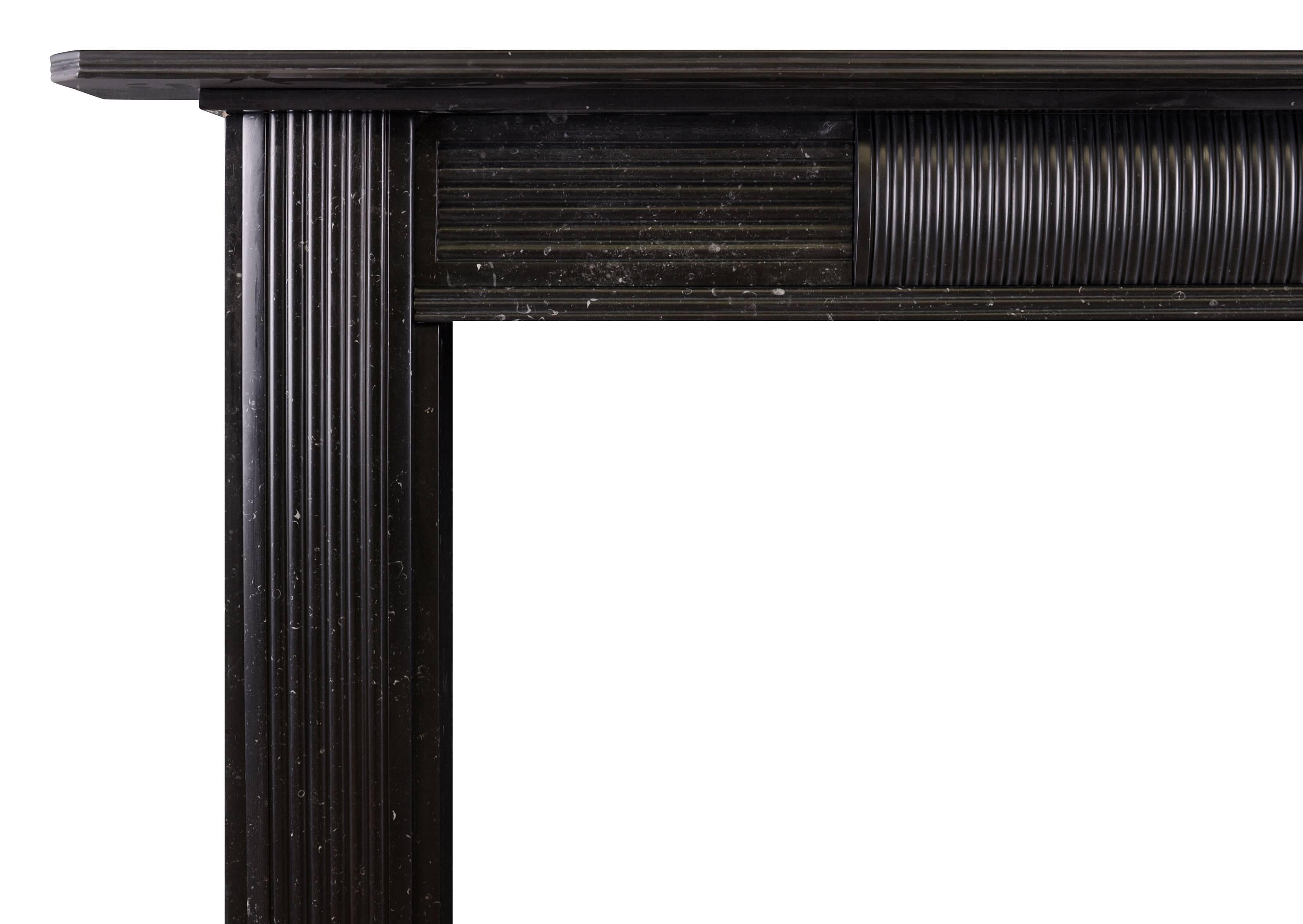 An English Regency marble fireplace in black Kilkenny marble. The reeded jambs surmounted by plain frieze with accompanying reeded centre block. Shaped shelf above. Part of a near pair with Stock No. 4304. A striking piece in an increasingly rare
