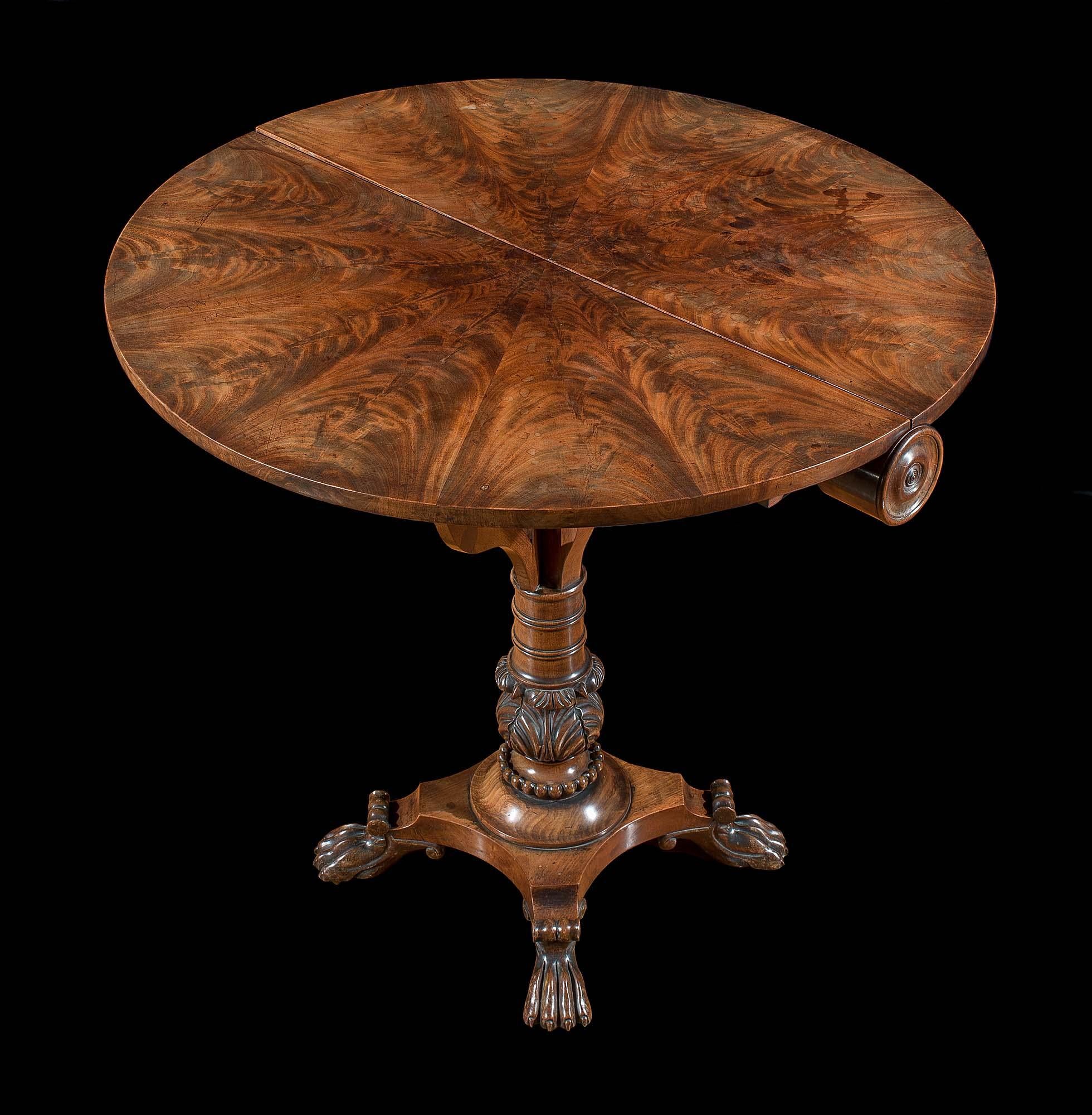 An early 19th century flame mahogany Regency drop-leaf Sutherland table in the manner of Thomas Hope.
The top is veneered in book matched plain mahogany. The turned central baluster pedestal, heavily carved with acanthus detail, is supported on