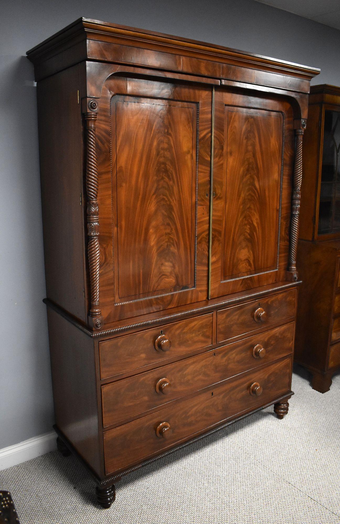 For sale is a good quality Regency flame mahogany linen press. The cornice, above two flame mahogany paneled doors, opening to two original linen trays, flanked by finely turned columns, above a chest base comprising two short drawers over two long