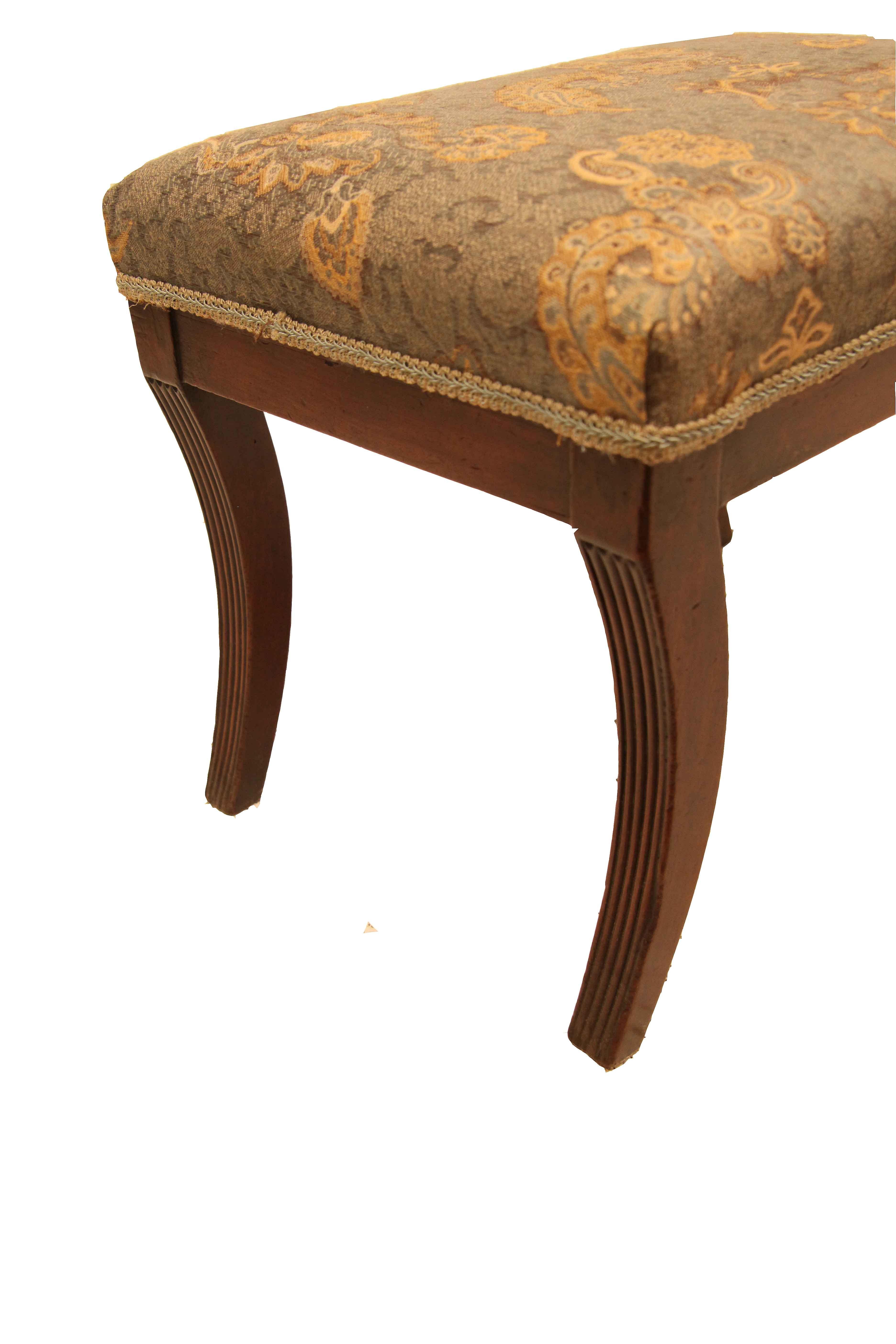 Regency foot stool, the legs with a beautiful sweeping concave shape have a reeded outer edge. The stool has been reupholstered in the latter part of the 20th century with a bold paisley pattern fabric. This stool is very sturdy .