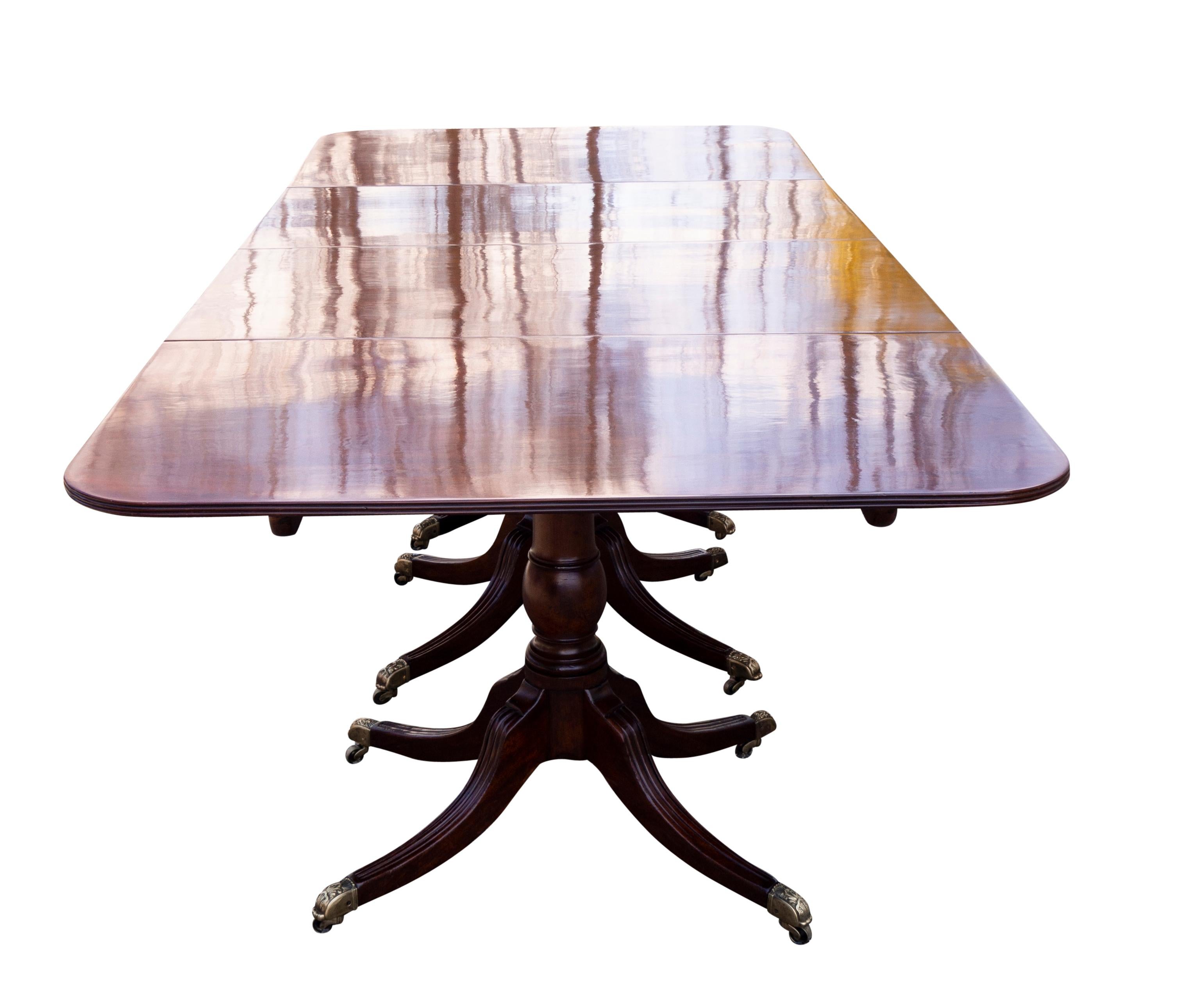 Fabriqué en acajou dense de la plus haute qualité. Quatre piédestaux avec chacun un plateau et trois feuilles supplémentaires. Quatre supports de balustres tournés se terminant par quatre pieds sabres cannelés avec des roulettes à godets en laiton.