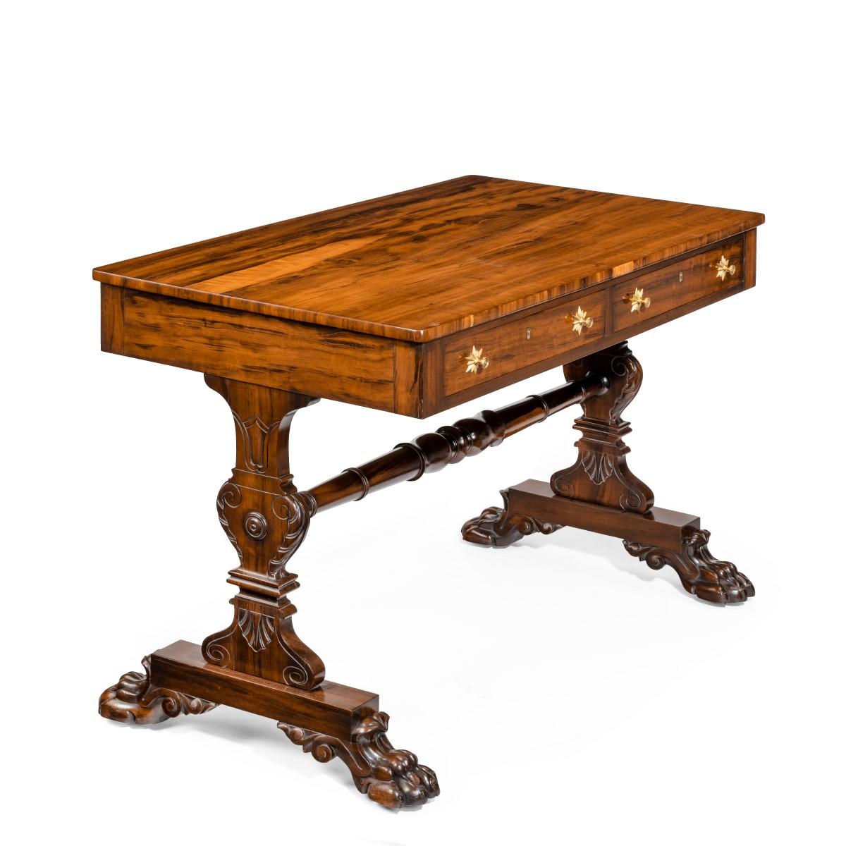 A late Regency free standing Gonzalo Alves writing table or library table, the rectangular top set above two frieze drawers on one side and dummy drawers to the reverse, raised upon end supports in the form of vases carved with scrolls and foliage