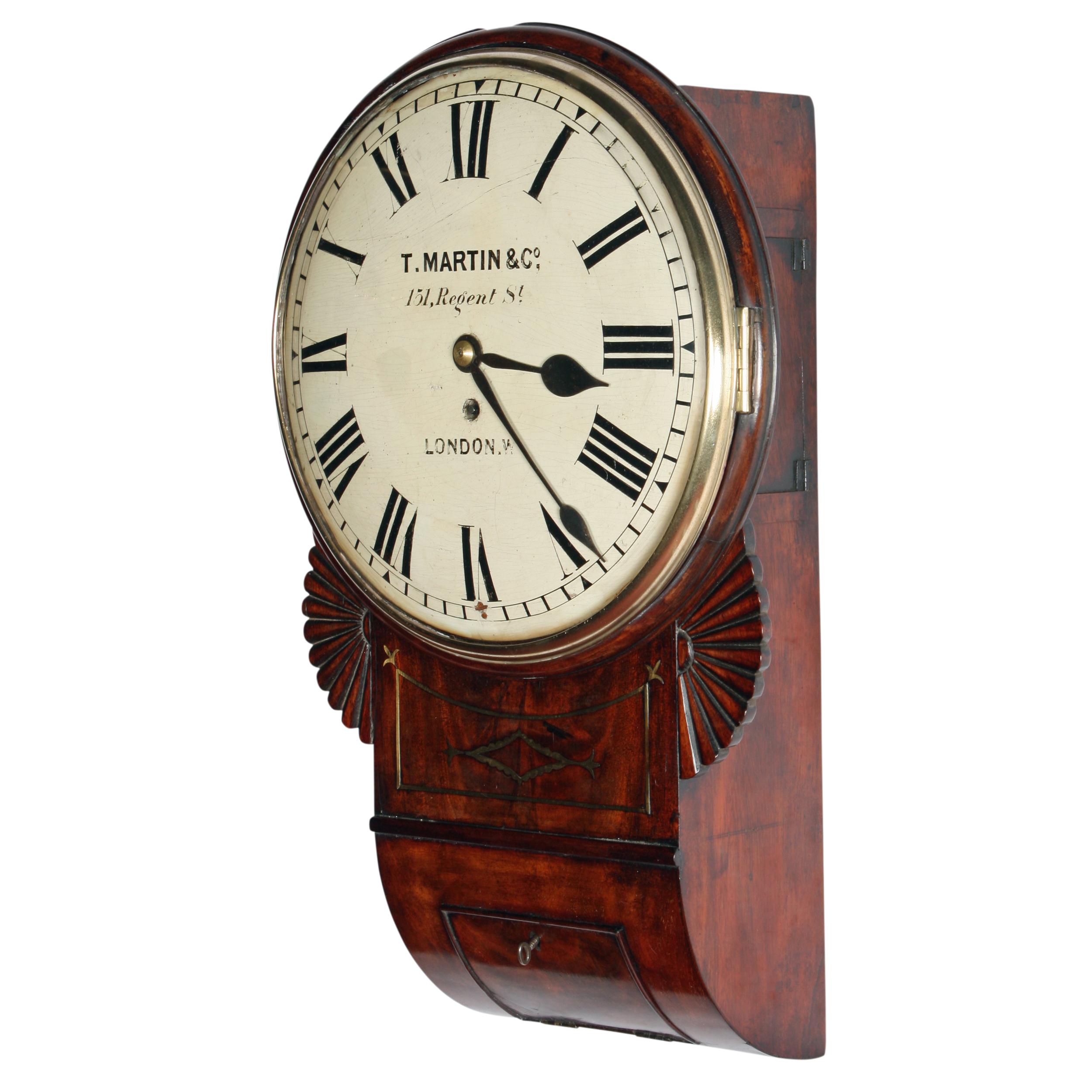 An early 19th century Regency mahogany and brass inlaid drop case fuse works wall clock.

The clock has a domed dial with Roman numerals and a domed glass held in a brass bevel.

The works are an eight day fusee movement with a brass pendulum