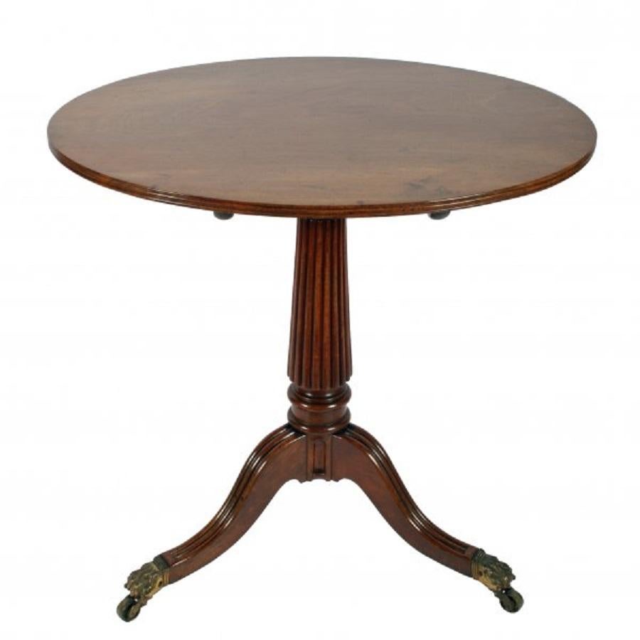 A Regency oval mahogany tip top tripod table made in a Gillows style.

The one piece oval top has a reeded edge and has a brass release catch underneath that allows the top to tip on a mahogany block.

The base has a reeded tapering stalk and