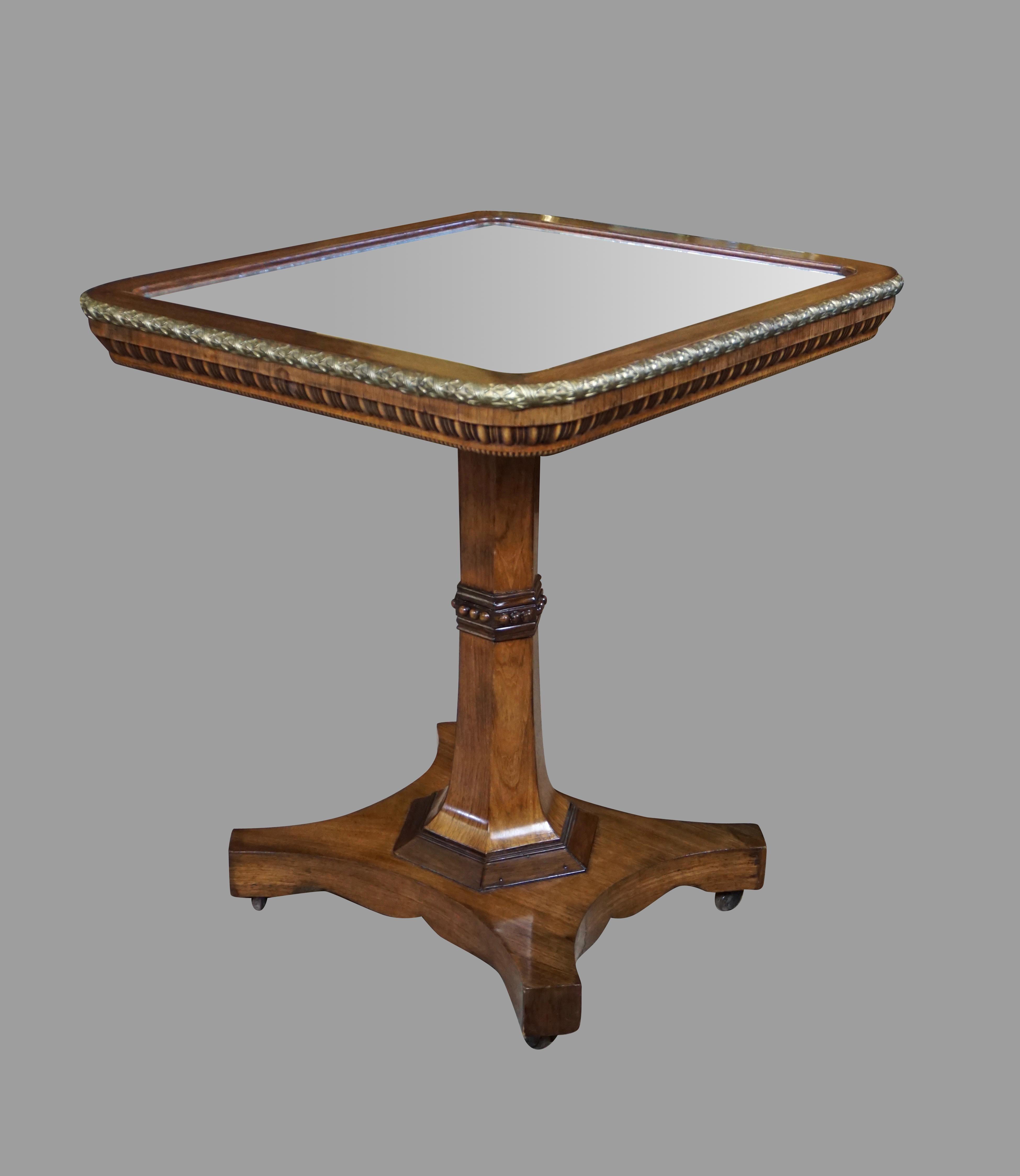 A stylish and fine quality Regency period rosewood tilt-top occasional table with an inset mirrored top, framed by a gilt metal edge, the side with gadrooned decoration, supported on a hexagonal column with central applied decoration terminating in