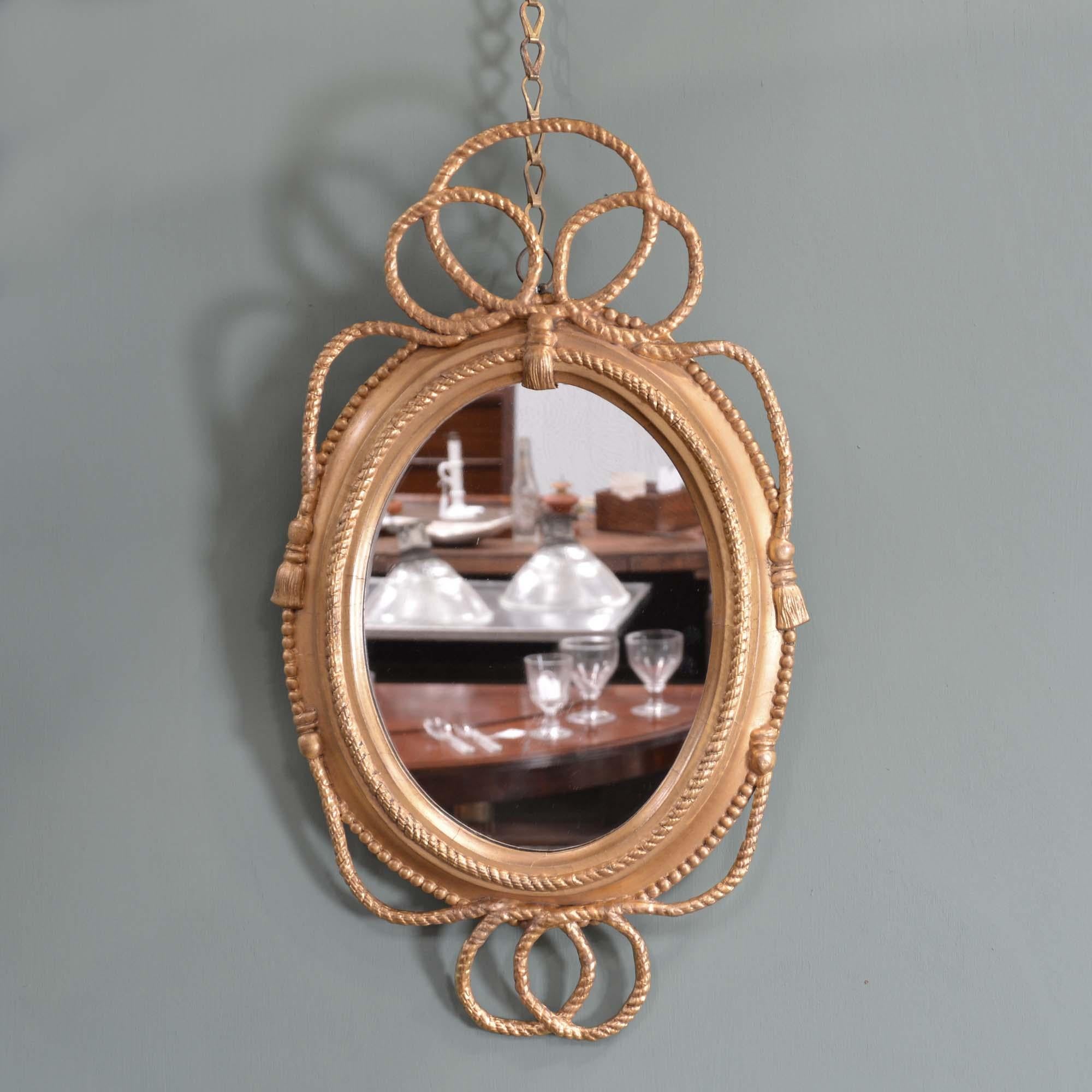 Specchio ovale dorato Regency
La cornice ovale in legno dorato è decorata con intrecci di corda e nappe, mentre la piastra dello specchio è successiva.
Inglese, circa 1820.

