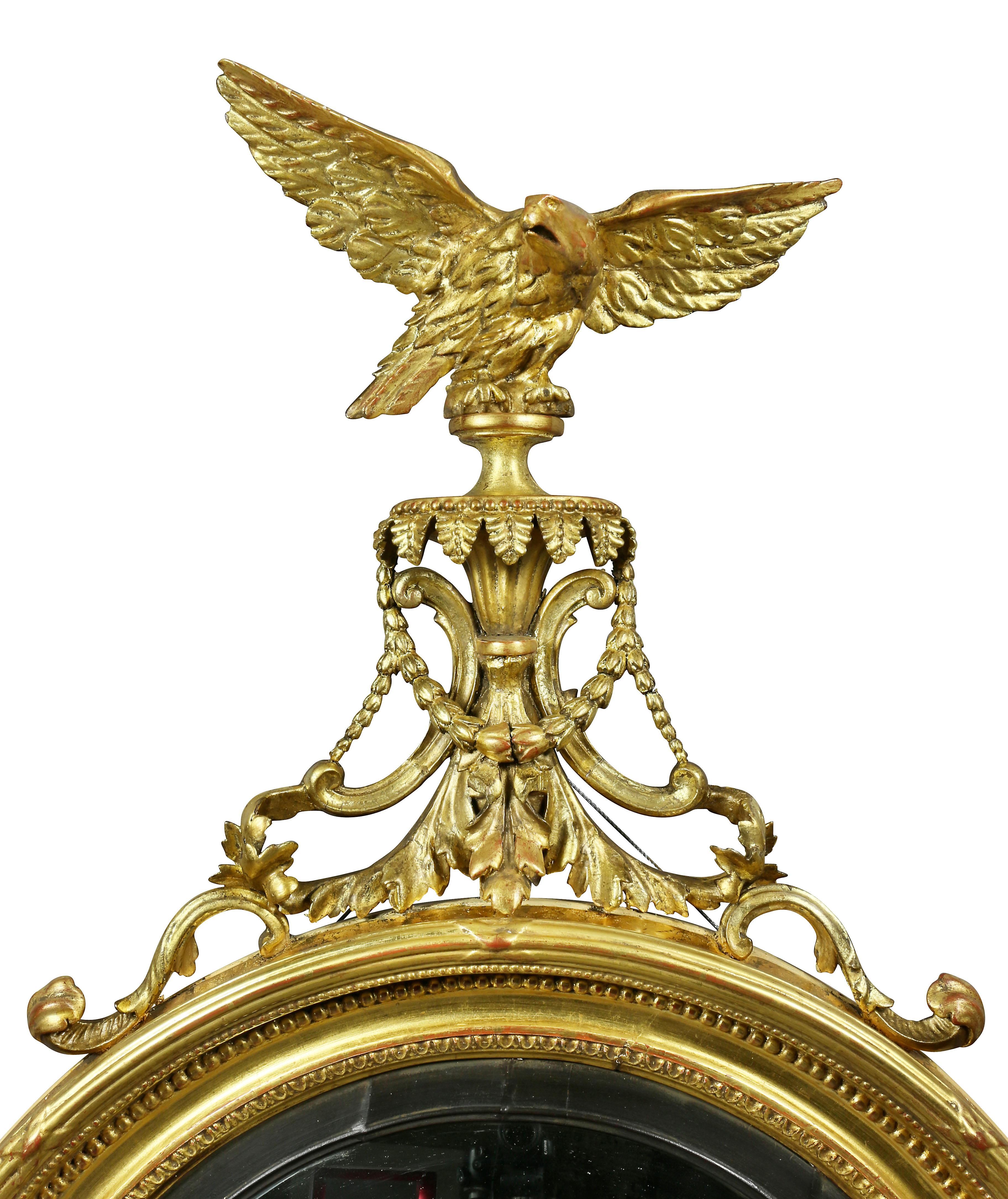With eagle finial with outspread wings over bellflower and acanthus carved plinth over a circular convex glass with black outer ring within a beaded and ribbon and reed frame, base with applied acanthus carving.